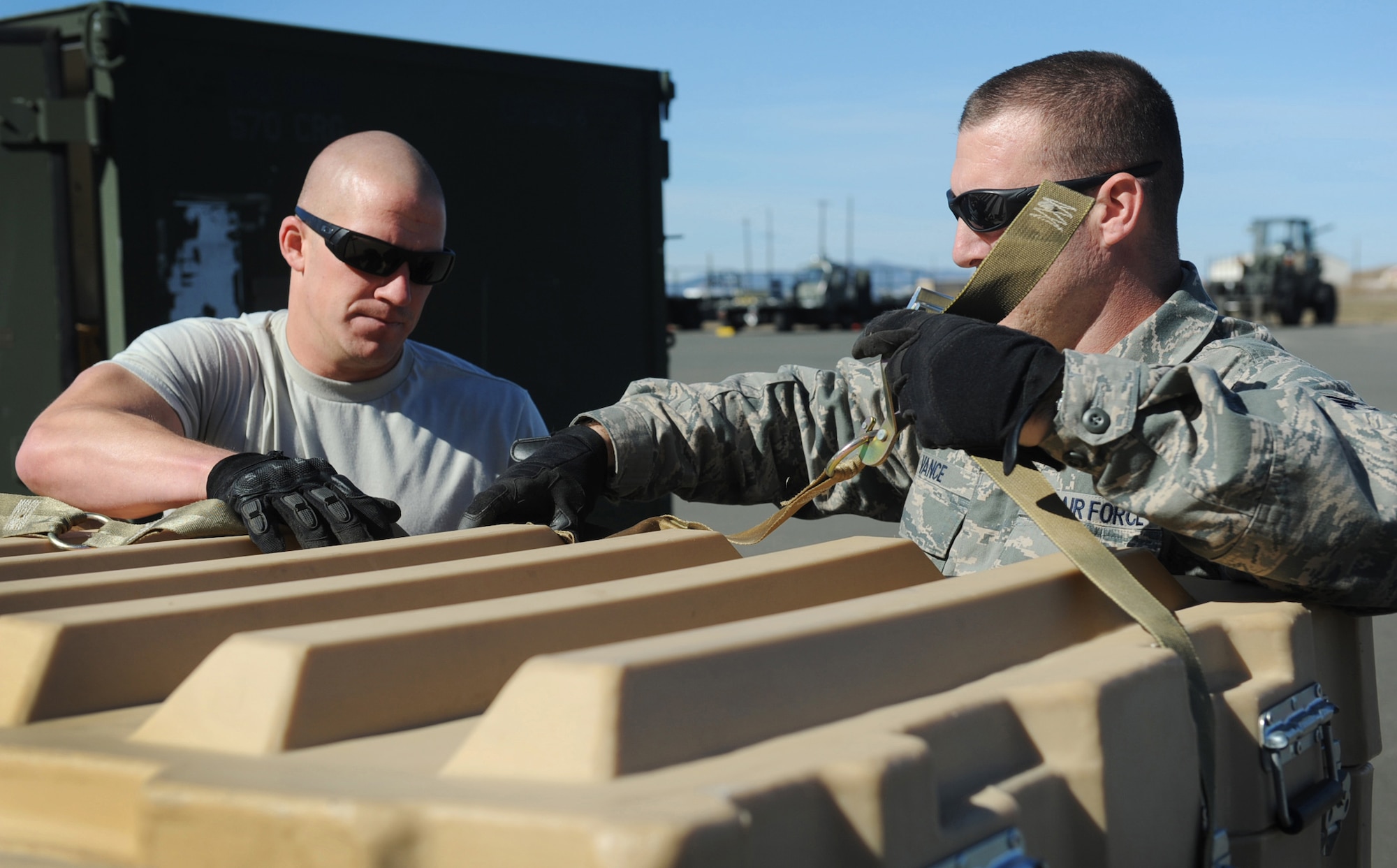Staff Sgt. Merrill Slepica, 570th GMS, and Staff Sgt. Joshua Vance, 573rd GSS, ensure pallet cargo straps are secured prior to a joint inspection during the 60 AMW conducted SAV for the upcoming LCAP. (U.S. Air Force Photo/ Master Sgt. Stan Parker)