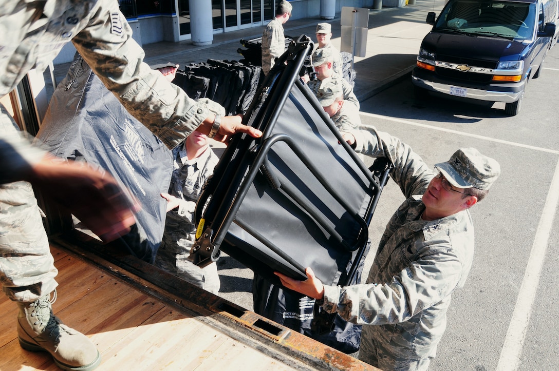 Col. Peter J. DePatie, commander, 103rd Air and Space Operations Group, hands an emergency cot to another Airman loading up a truck destined for a shelter at Vernon Center Middle School in Vernon, Conn. Nov. 1, 2011. The Airmen loaded 92 cots as part of the relief effort to assist residents of Connecticut after the destruction caused by Storm Alfred on Oct. 29, 2011. (U.S. Air Force photo by Tech. Sgt. Erin McNamara)