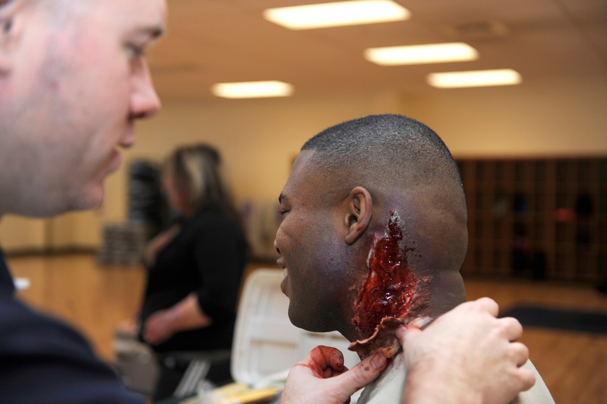 Will Enfinger, left, creates a simulated wound on Senior Airman Chris Cooper's neck in preparation for a simulated zombie invasion in the Joint Base Elmendorf-Richardson Fitness Center Oct. 31, 2011. Zombies were chosen in the spirit of the Halloween season and used to help the moulage team practice their skills. Enfinger is a simulation operator for the hospital's Simulation Center, which specializes in creating realistic wounds and scenarios. Cooper is a 525th Aircraft Maintenance F22 crew chief. (U.S. Air Force photo/Staff Sgt. Robert Barnett/Released)