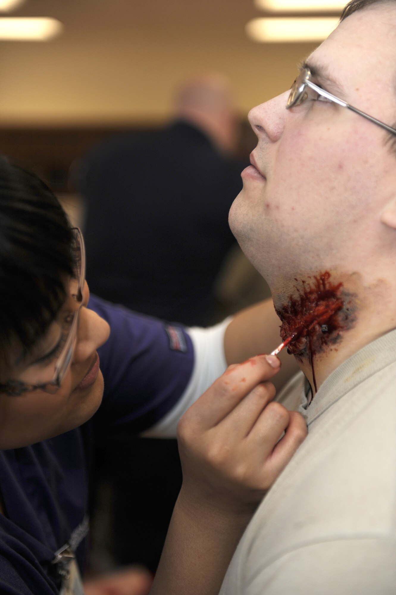 Marissa Carrillo, left, creates a simulated wound on Senior Airman Christopher Miller's throat in preparation for a simulated zombie invasion in the Joint Base Elmendorf-Richardson Fitness Center Oct. 31, 2011. Zombies were chosen in the spirit of the Halloween season and used to help the moulage team practice their skills. Carrillo is a simulation operator for the University of Alaska in Anchorage, partnering withhospital's Simulation Center, which specializes in creating realistic wounds and scenarios. Miller is a 525th Aircraft Maintenance F22 crew chief. (U.S. Air Force photo/Staff Sgt. Robert Barnett/Released)