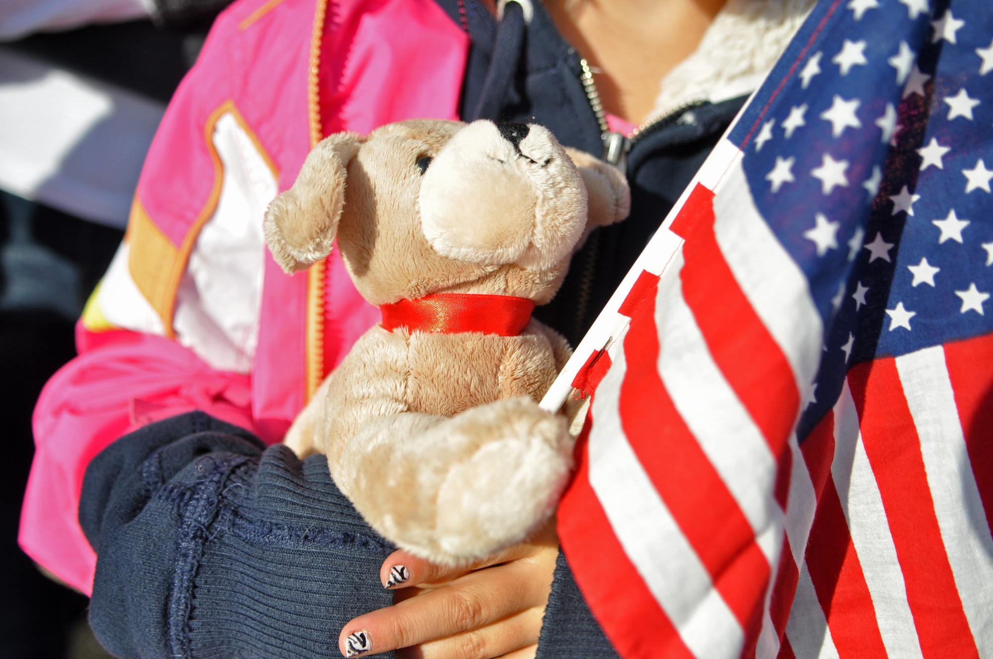 The daughter of an 8th Airlift Squadron pilot holds a toy dog and American flag while waiting for her father’s return from a 67-day deployment Nov. 3, 2011, at Joint Base Lewis-McChord, Wash. According to Airmen of the 8th AS, the mission would not have been a success without the constant support from loved ones back home.  (U.S. Air Force photo/Airman 1st Class Leah Young)