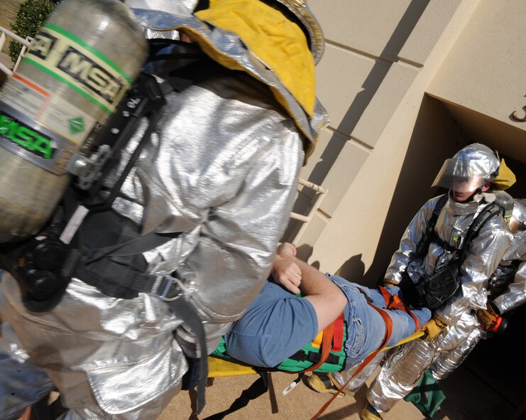 Fire-fighters from the 2nd Civil Engineer Squadron carry a simulated tornado victim on a stretcher during a Major Accident Response Exercise on Barksdale Air Force Base, La., Nov. 1. The fire-fighters rescued and retrieved 14 simulated tornado victims from the building. (U.S. Air Force photo/Airman 1st Class Micaiah Anthony)(RELEASED)