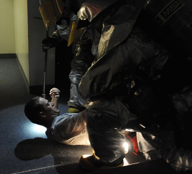 Fire-fighters from the 2nd Civil Engineer Squadron check a simulated tornado victim's vital signs during a Major Accident Response Exercise on Barksdale Air Force Base, La., Nov. 1. Once the victim was stable, fire-fighters escorted the victim to safety and continued their search for other victims. (U.S. Air Force photo/Airman 1st Class Micaiah Anthony)(RELEASED)