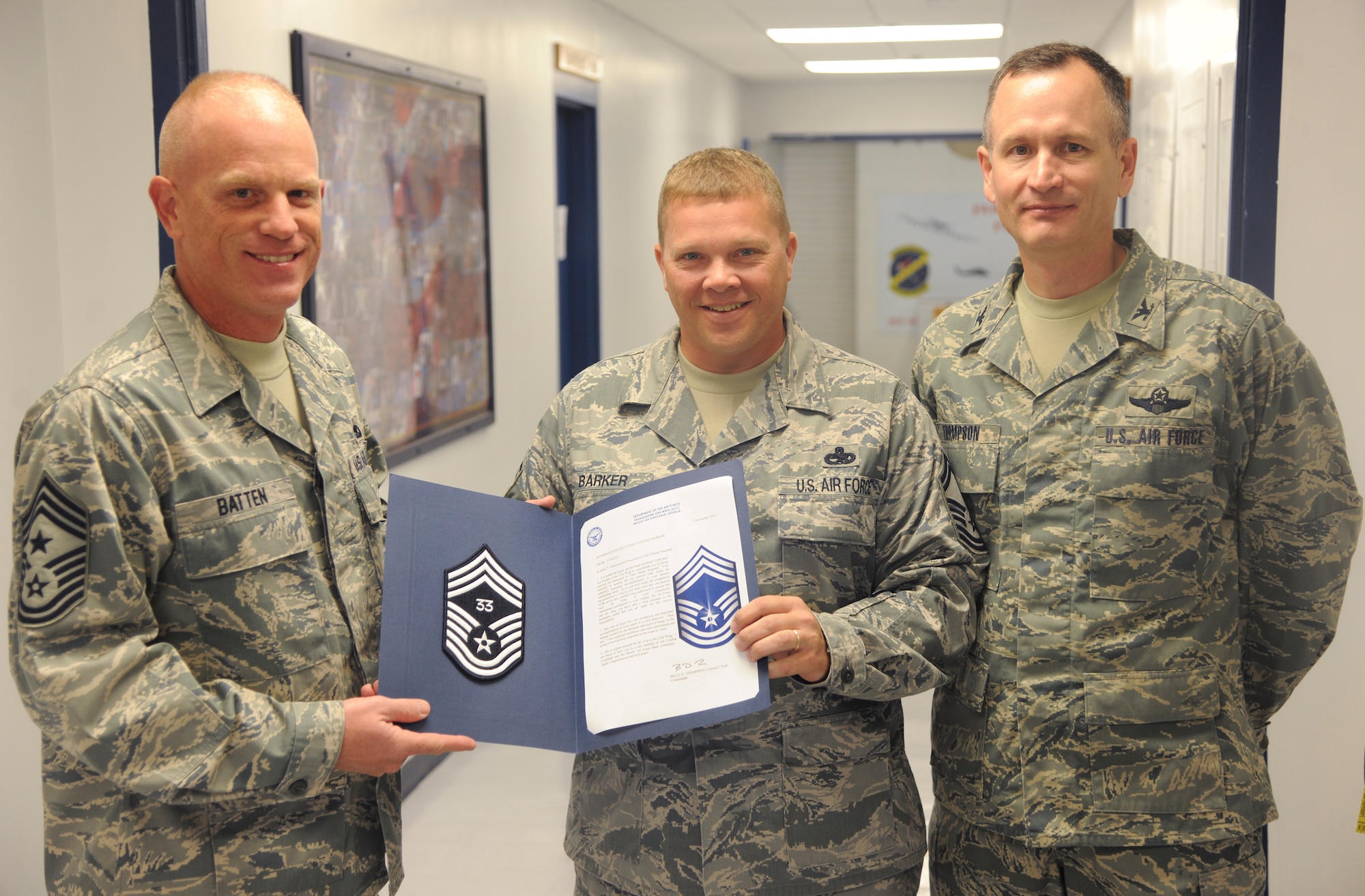 U.S. Air Force Chief Master Sgt. Frank Batten, 23rd Wing command chief, and Col. Billy Thompson, 23rd Wing commander, award a certificate to Senior Master Sgt. David Barker, 23rd Component Maintenance Squadron lead production superintendent, on his selection for chief master sergeant at Moody Air Force Base, Ga., Nov. 3, 2011. Barker was greeted and congratulated by Batten, Thompson and many of his friends and co-workers. (U.S. Air Force photo by Airman 1st Class Paul Francis/Released) 

