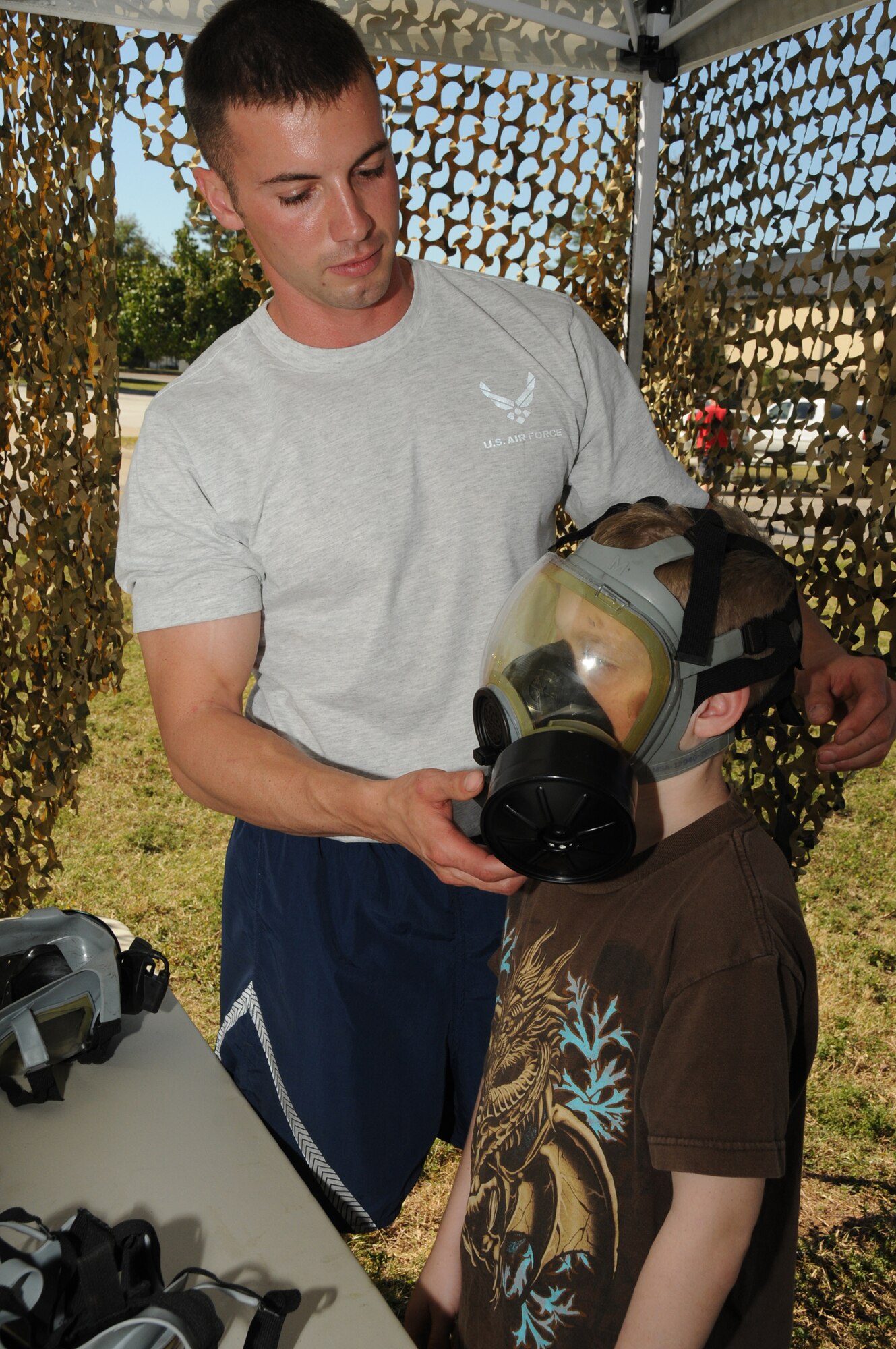 Senior Airman Branden Fox, 345th Airlift Squadron, fits a gas mask on Montgomery Wilson, 10, son of Master Sgt. Gregory and Rebecca Wilson, 85th Engineering Installation Squadron, during Operation Hero Oct. 15, 2011, Keesler Air Force Base, Miss.  MSgt. Wilson is currently deployed to Afghanistan.  Operation Hero is presented twice a year to give parents a chance to expose their children to what happens when they leave home for deployment tasking or temporary duty.   (U.S. Air Force photo by Kemberly Groue)