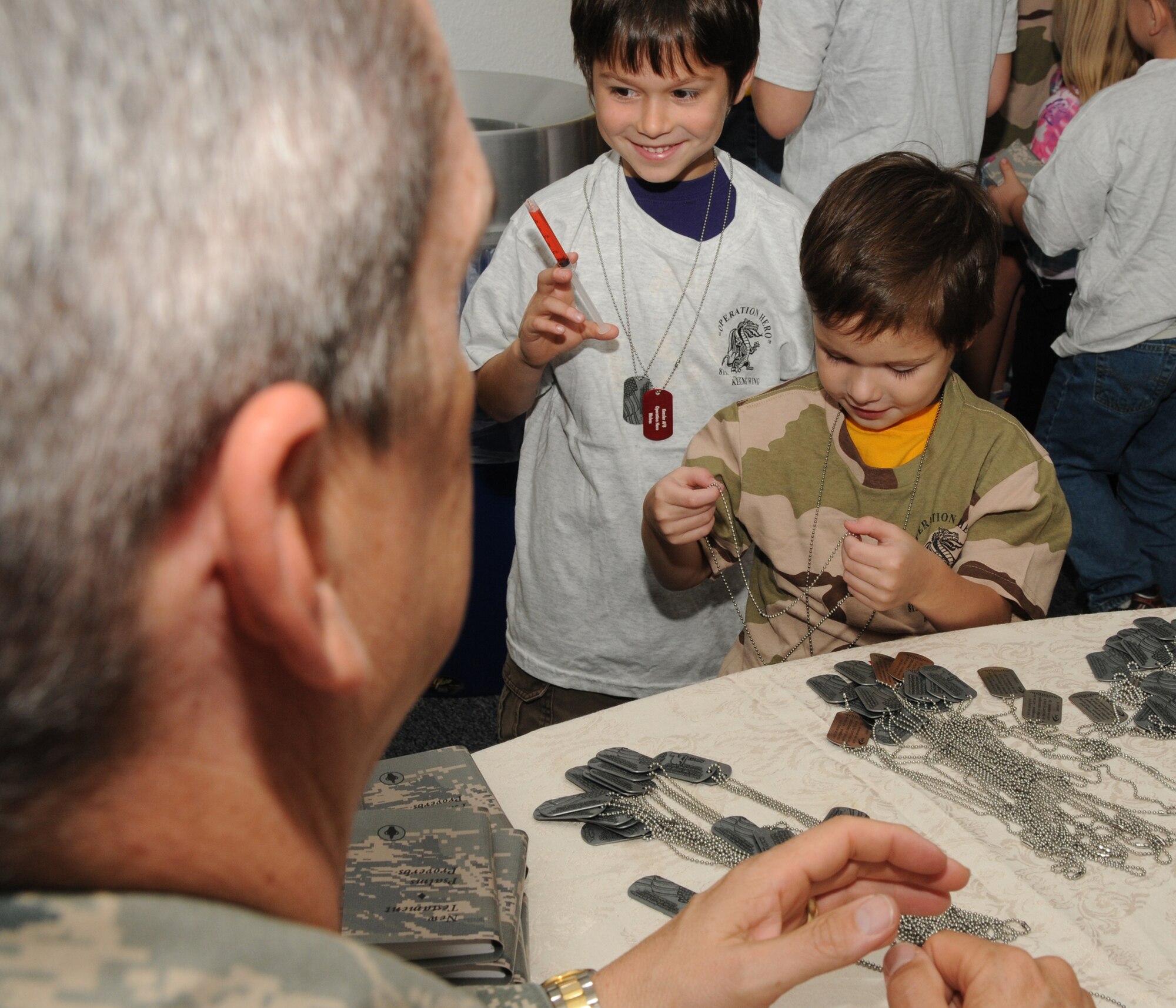 Left, Chaplain (Maj.) Mark Thomas, 81st Training Wing, Keesler Air Force Base, Miss., hands out dog tags to Zayne Saujon, 6, and his brother, Llandyn, 4, dependants of Staff Sgt. Nathaniel and Mandy Saujon, 81st Medical Operations Squadron, during Operation Hero Oct. 15, 2011.  Operation Hero is presented twice a year to give parents a chance to expose their children to what happens when they leave home for deployment taskings or temporary duty.  (U.S. Air Force photo by Kemberly Groue)