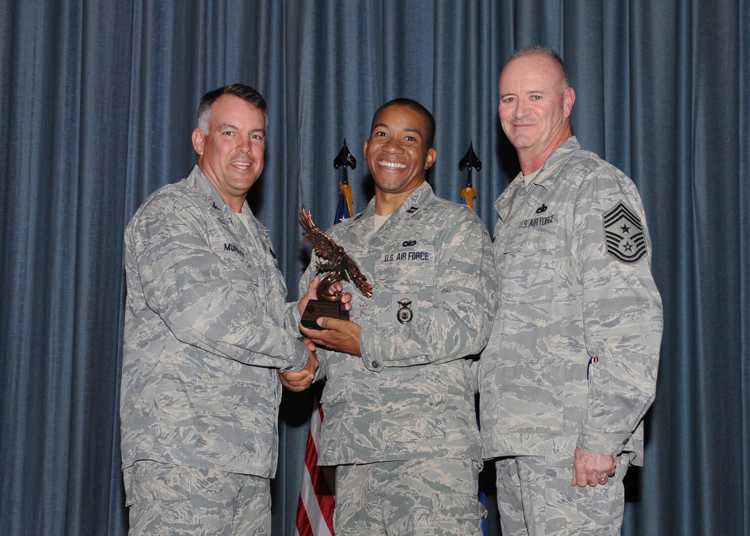 Col. Richard Murphy, 12th Flying Training Wing Commander, and Chief Master Sgt. Steven Jones, 12th FTW command chief, presents Capt. Antwan Floyd, 902nd Security Forces Squadron, with the Company Grade Officer of the Quarter award during the Joint Base San Antonio Randolph 3rd Quarter Award Ceremony at the base theater at Randolph Air Force Base, Texas, Nov. 2.(U.S. Air Force photo/Melissa Peterson)