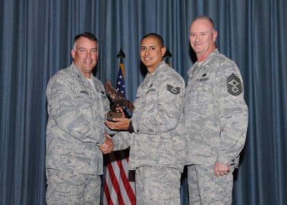 Col. Richard Murphy, 12th Flying Training Wing Commander, and Chief Master Sgt. Steven Jones, 12th FTW command chief, presents Staff Sgt. Isae Alvarado, Randolph Honor Guard, with the noncommissioned officer of the Quarter Award during the Joint Base San Antonio Randolph 3rd Quarter Award Ceremony in the base theater at Randolph Air Force Base, Texas, Nov. 2. (U.S. Air Force photo/Melissa Peterson)