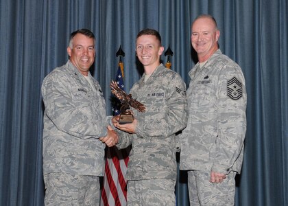 Col. Richard Murphy, 12th Flying Training Wing Commander, and Chief Master Sgt. Steven Jones, 12th FTW command chief, presents Senior Airman Ronald Albright, Randolph Honor Guard, with the Airman of the Quarter Award during the Joint Base San Antonio Randolph 3rd Quarter Award Ceremony at the base theater at Randolph Air Force Base, Texas, Nov. 2. (U.S. Air Force photo/Melissa Peterson)