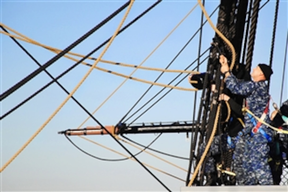 Navy Seaman Michael Achterling ties a block to the main topsail shrouds in preparation to take the sail off USS Constitution for winter stowage in Charlestown, Mass., Nov. 2, 2011.