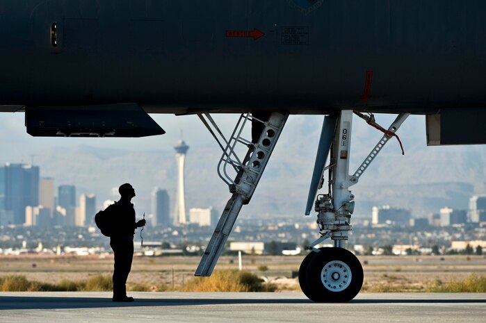 U.S. Air Force Airman 1st Class Adeyinka Adenikinju, crew chief, 7th Aircraft Maintenance Squadron, Dyess Air Force Base, Texas, looks underneath a B-1 Lancer during the integrated tactics phase of the U.S. Air Force Weapons School Nov. 3, 2011, at Nellis Air Force Base, Nev. The 77th Weapons Squadron, part of the U.S.A.F.W.S., provides instructional flying and tactics training for students piloting the B-1 Lancer. (U.S. Air Force photo by Senior Airman Brett Clashman/Released)