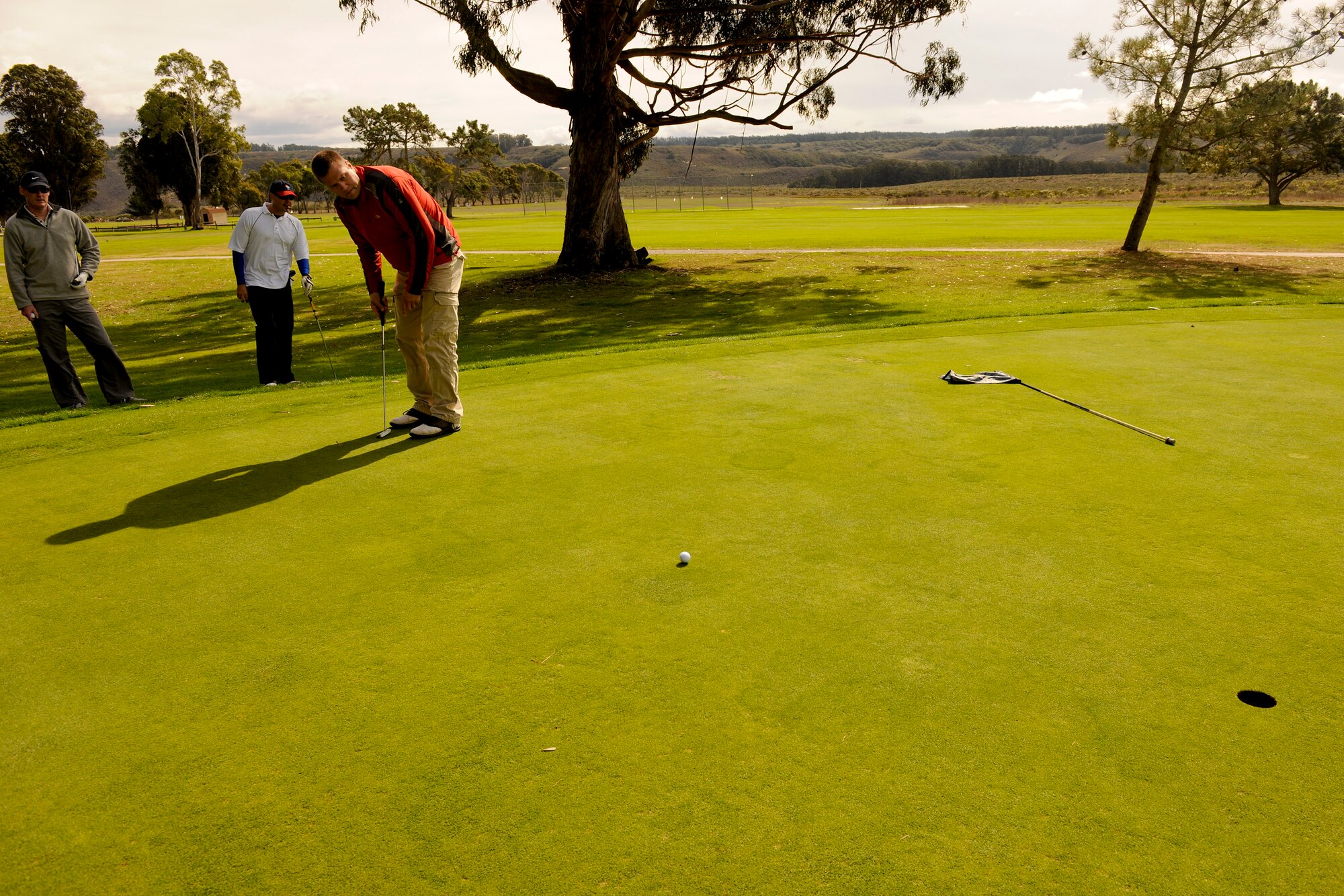 VANDENBERG AIR FORCE BASE, Calif. -- Golfers watch as Todd Ranney attempts to make a putt during a golf tournament hosted by members of Vandenberg's Commonwealth here Friday, Nov. 4, 2011. The event was a small gesture of appreciation for Vandenberg members for helping the Commonwealth personnel and their families feel welcome while thousands of miles away from their homeland. (U.S. Air Force/Staff Sgt. Levi Riendeau)