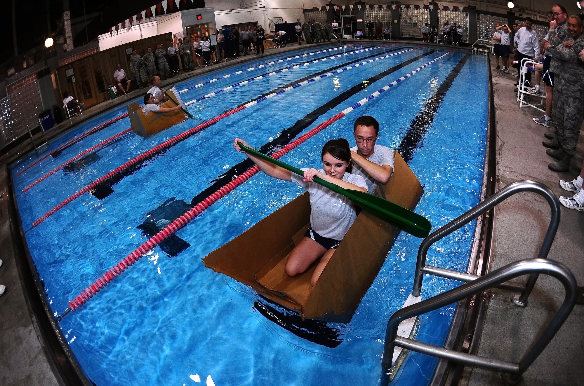The 55th Contracting Squadron (top) and the 55th Strategic Communications Squadron (bottom), battle it out in cardboard boats to see who can stay afloat the longest on the field house indoor pool at Offutt Air Force Base, Neb., Nov. 4.  Participants in the boat race had only twenty minutes to engineer a boat using duct tape and sheets of cardboard prior to the race. (U.S. Air Force photo by Josh Plueger/Released