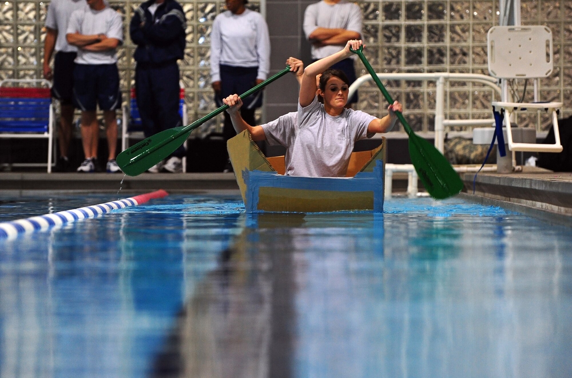 U.S. Air Force 2nd Lt. Riane Charbonneau and Staff Sgt. Alfred Shell, 55th Strategic Communications Squadron, paddle their cardboard boat along the indoor pool located in the field house at Offutt Air Force Base, Neb., Nov. 4.  Participants in the boat race had only twenty minutes to engineer a boat using duct tape and sheets of cardboard prior to the race. (U.S. Air Force photo by Josh Plueger/Released)