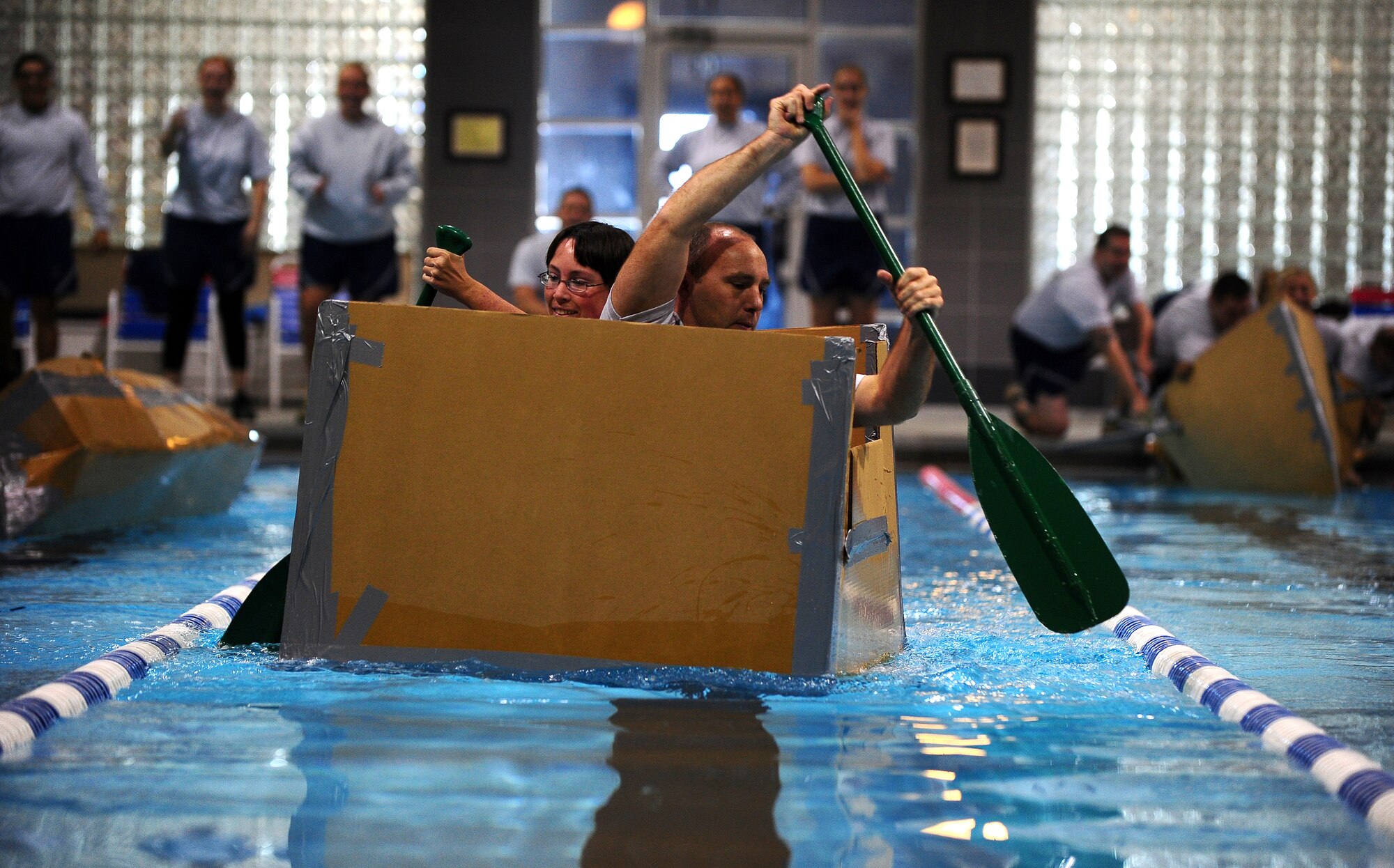 U.S. Air Force Senior Airman Stephanie Warner and Staff Sgt. Own Hurley, 55th Contracting Squadron, navigate their cardboard boat along the indoor pool located in the field house, at Offutt Air Force Base, Neb., Nov. 4.  Team Offutt members participated in the annual Wingman Day which included the cardboard boat racing, along with activities designed to promote teamwork and camaraderie. (U.S. Air Force photo by Josh Plueger/Released)