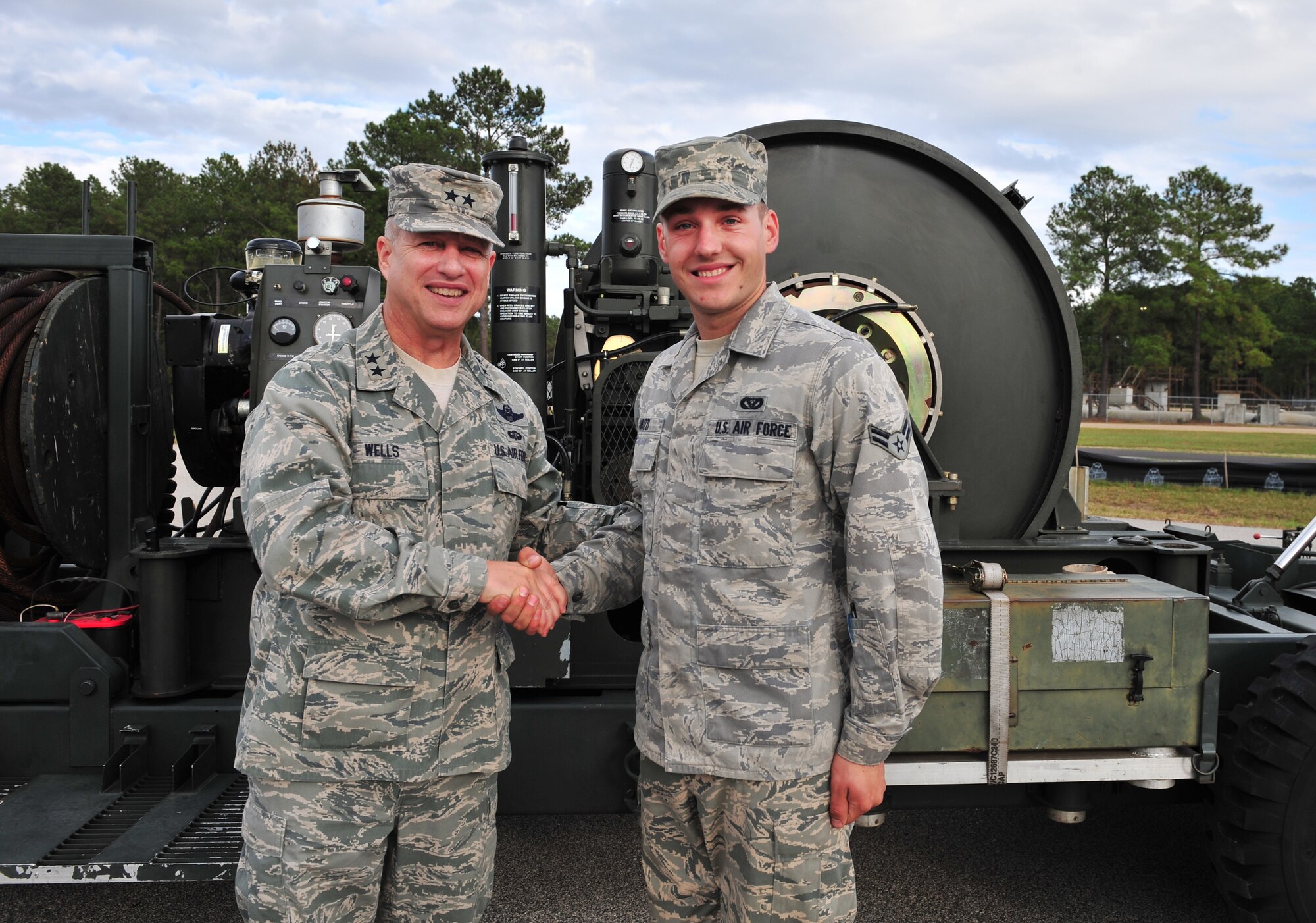 U.S. Air Force Maj. Gen. Lawrence Wells, 9th Air Force commander, shakes the hand of, Airman 1st Class Dominic Januzzi, 20th Civil Engineer Squadron power pro apprentice, after coining him Nov. 3, 2011, Shaw Air Force Base, S.C.  Januzzi is one of a few Airmen capable of installing and operating a BAK-12, Barrier Arrestor Kit, Mobile Aircraft Arresting System. The BAK-12 is used to slow down aircraft in short distances, ideal for areas with little space for runways. (U.S. Air Force photo by Airman 1st Class Amber E. N. Jacobs/Released) 