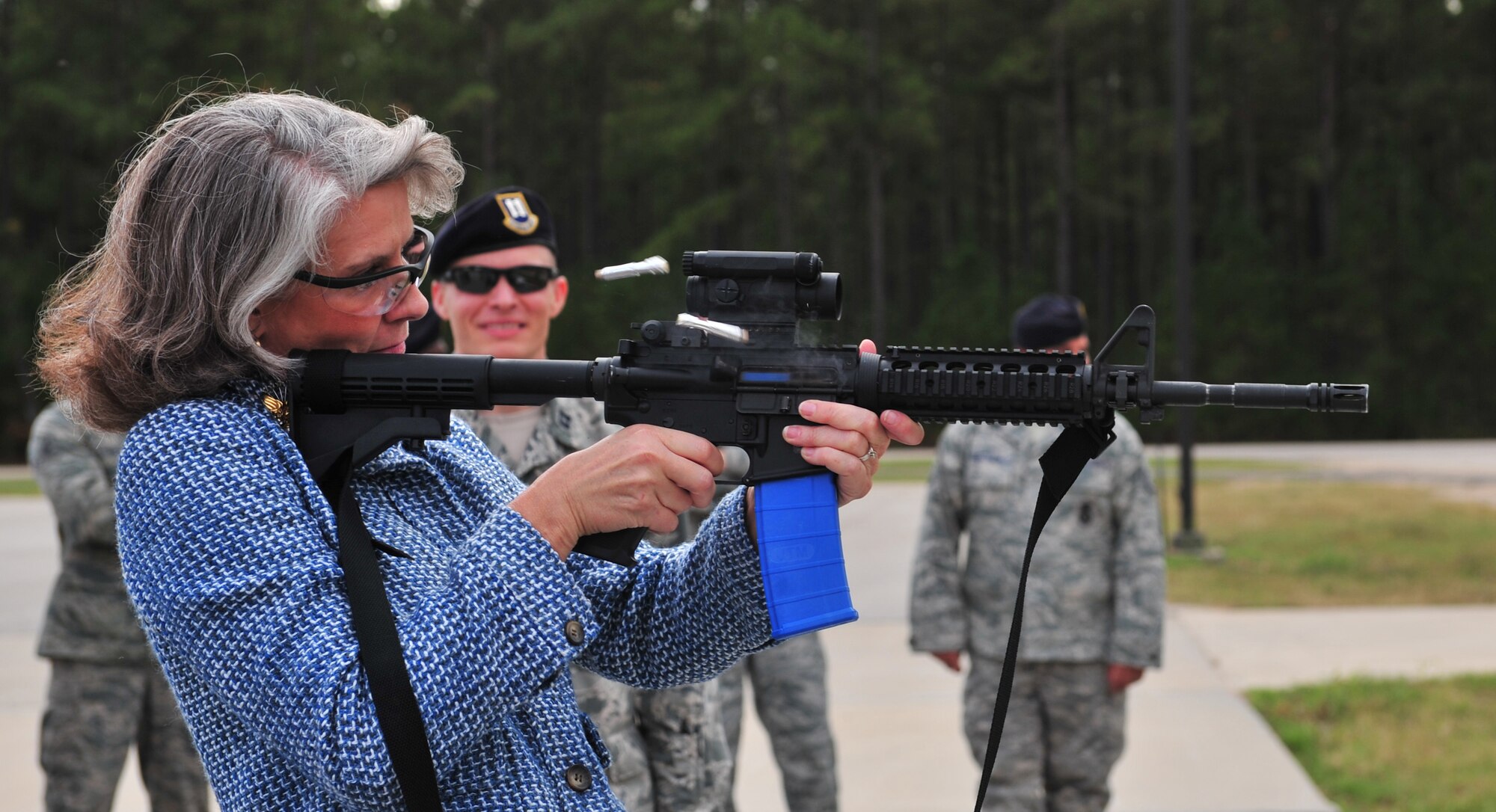 Mrs. Kathy Wells, wife of 9th Air Force commander, Maj. Gen. Lawrence Wells, fires a training M-4 loaded with simulated rounds at nearby targets, while Capt. David Celeste, 20th Security Forces Squadron operations officer, watches Nov. 3, 2011, Shaw Air Force Base, S.C. The training rounds used are similar to paint ball rounds with a weaker jacket. They fire with much less force that a regular round, allowing for a safe training environment while remaining similar to a real firing exercise. (U.S. Air Force photo by Airman 1st Class Amber E. N. Jacobs/Released) 