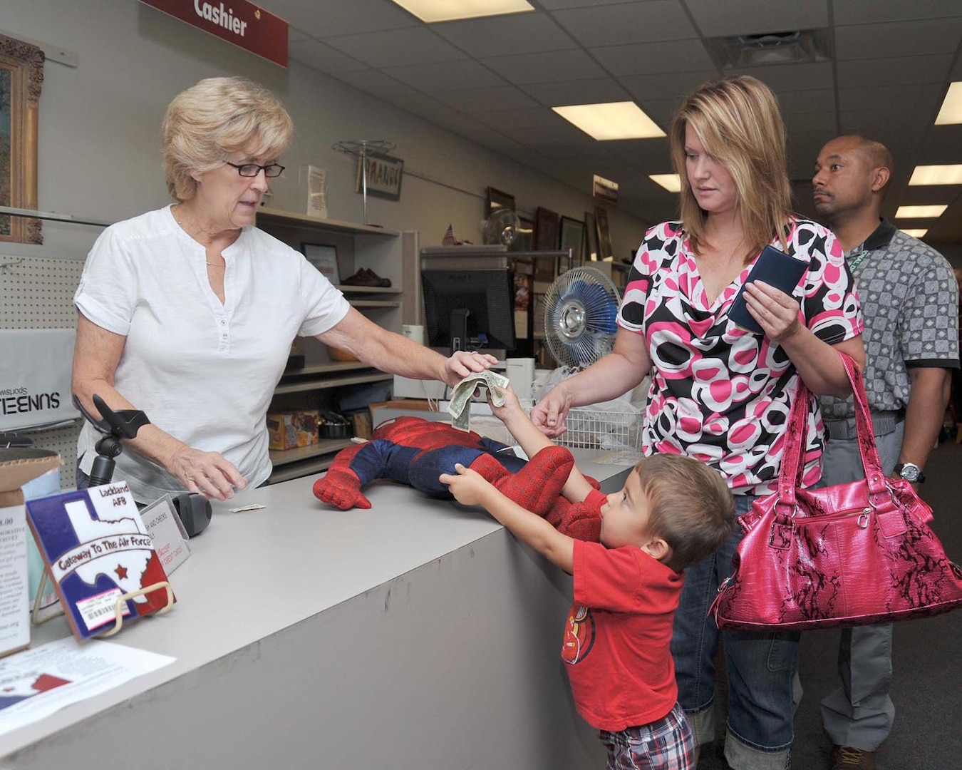 Twila Garcia looks on as son, Domenic, 3, pays thrift shop cashier June Christy for a Spiderman doll during the grand opening of the One Stop facility Sept. 28. Domenic’s father is Capt. Luis Garcia, 837th Training Squadron, Inter-American Air Forces Academy. Patrons wait patiently for the grand opening of the new One Stop facility Sept 28. (U.S. Air Force photo/Alan Boedeker)
