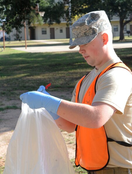 Airman 1st Class Ryan Beck, 2nd Comptroller Squadron customer service, places trash into a garbage bag behind the Hercules dorm Nov. 2 on Barksdale Air Force Base, La. He was chosen as part of the bay-orderly program to clean up the areas around the Airmen's dorms. (U.S. Air Force photo/Airman 1st Class Andrea F. Liechti)(RELEASED)