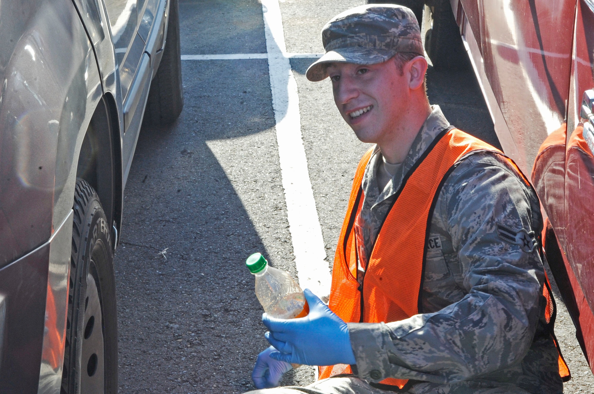 Airman 1st Class Dalton Clark, 2nd Aircraft Maintenance Squadron aircraft structural maintenance, picks up an empty bottle from underneath a car in the parking lot outside of the Stratofortress dorm Nov. 2 on Barksdale Air Force Base, La. He was chosen as part of the bay-orderly program to make sure the areas in and around the dorms are kept clean. (U.S. Air Force photo/Airman 1st Class Andrea F. Liechti)(RELEASED)