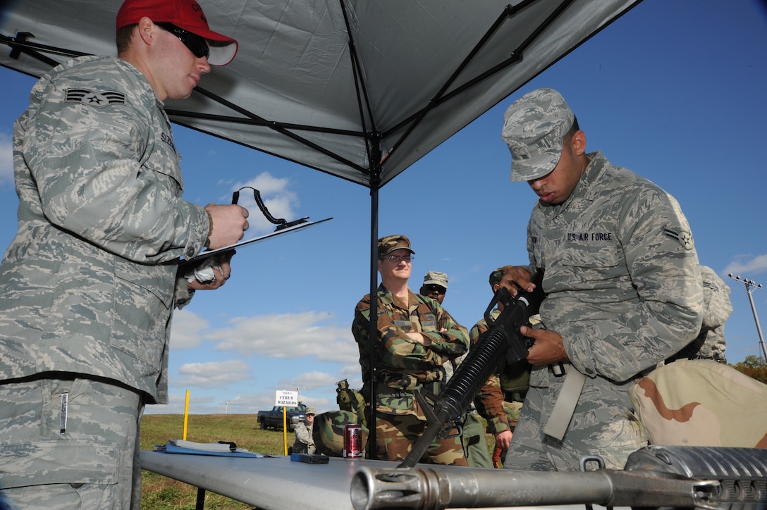 Airman 1st Class Jason Martin, 744th Communications Squadron cyber transport systems technician, assembles an M-16 rifle under the observation of Senior Airman Bryan Sizemore, 11th Security Forces Squadron Combat Arms Training and Maintenance instructor, during the rifle assembly and disassembly portion of the annual 844th Communications Squadron Warrior Day Competition. (U.S. Air Force photo/Airman 1st Class Bahja J. Jones)