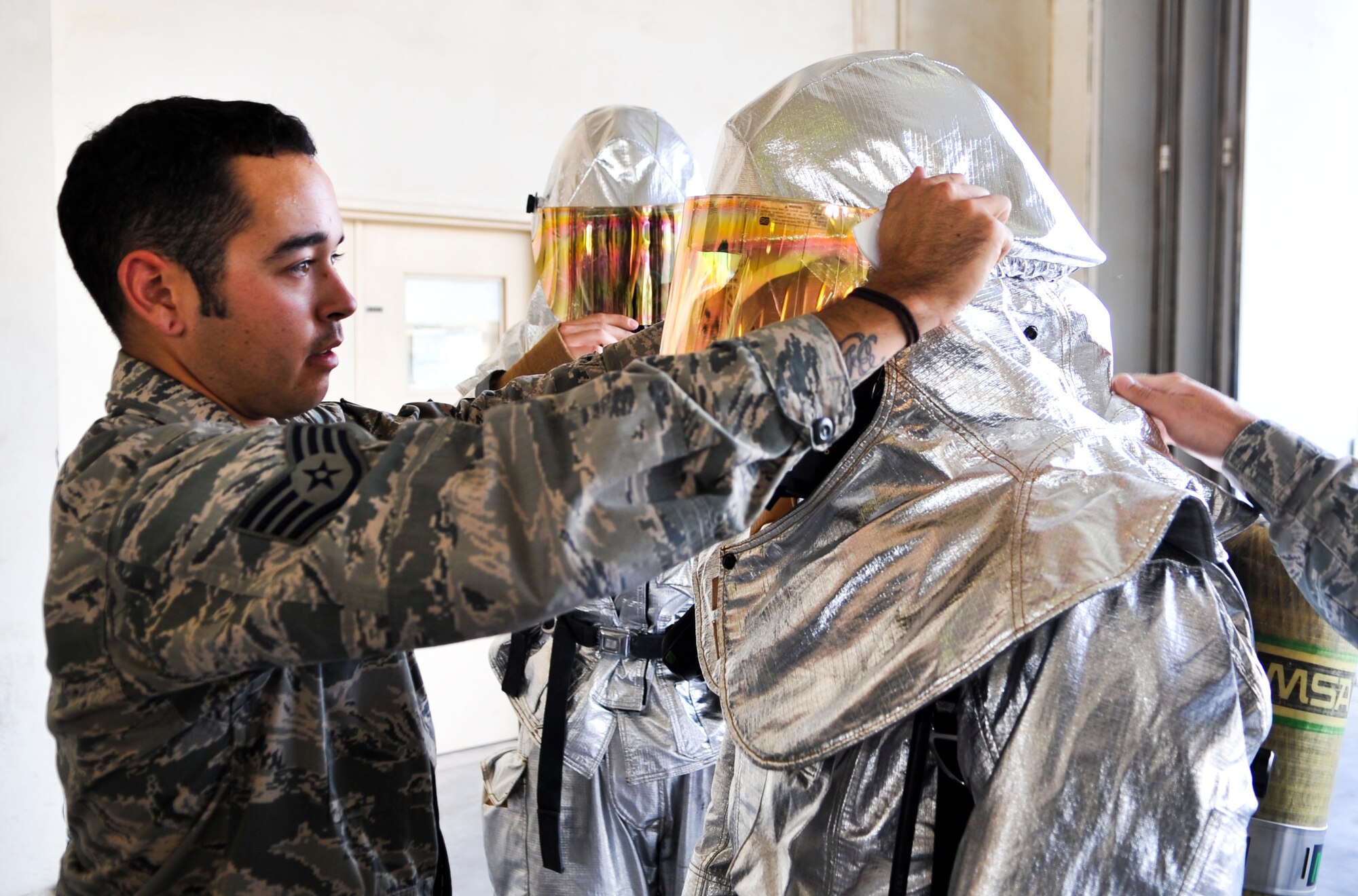 Staff Sgt. David Tyson, 379th Civil Engineer Squadron firefighter, helps Col. Giovanni Tuck, 379th Air Expeditionary Wing commander, adjusts his aluminized proximity helmet before beginning a training exercise Nov. 2, 2011, at an undisclosed location in Southwest Asia. Tyson, a native of Sacramento, Calif., is deployed from Royal Air Force Lakenheath, England. (U.S. Air Force photo/Senior Airman Paul Labbe)