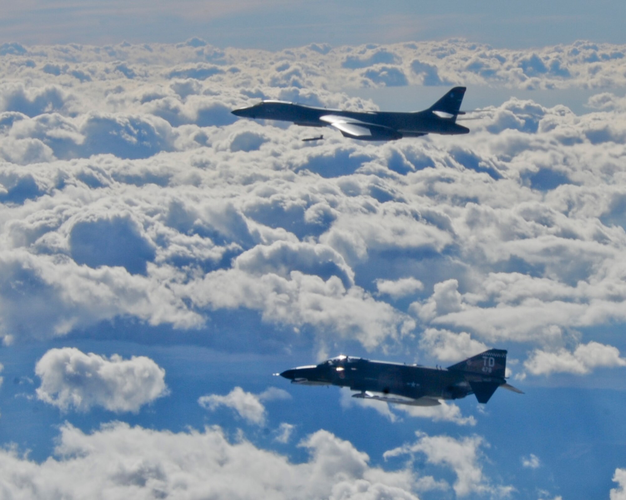 HOLLOMAN AIR FORCE BASE, N.M. -- A B-1B Lancer from Ellsworth Air Force Base, S.D., drops an AGM-158 Joint Air-to-Surface Standoff Missile Oct. 25, 2011, while an F-4 Phantom II flies chase during an air-to-ground Weapon System Evaluation Program known as Combat Hammer. The goal of Combat Hammer, managed by the 86th Fighter Weapons Squadron at Eglin Air Force Base, Fla., is to evaluate the effectiveness, maintainability, suitability and accuracy of precision guided munitions and other advanced air-to-ground weapons. (Courtesy Photo)