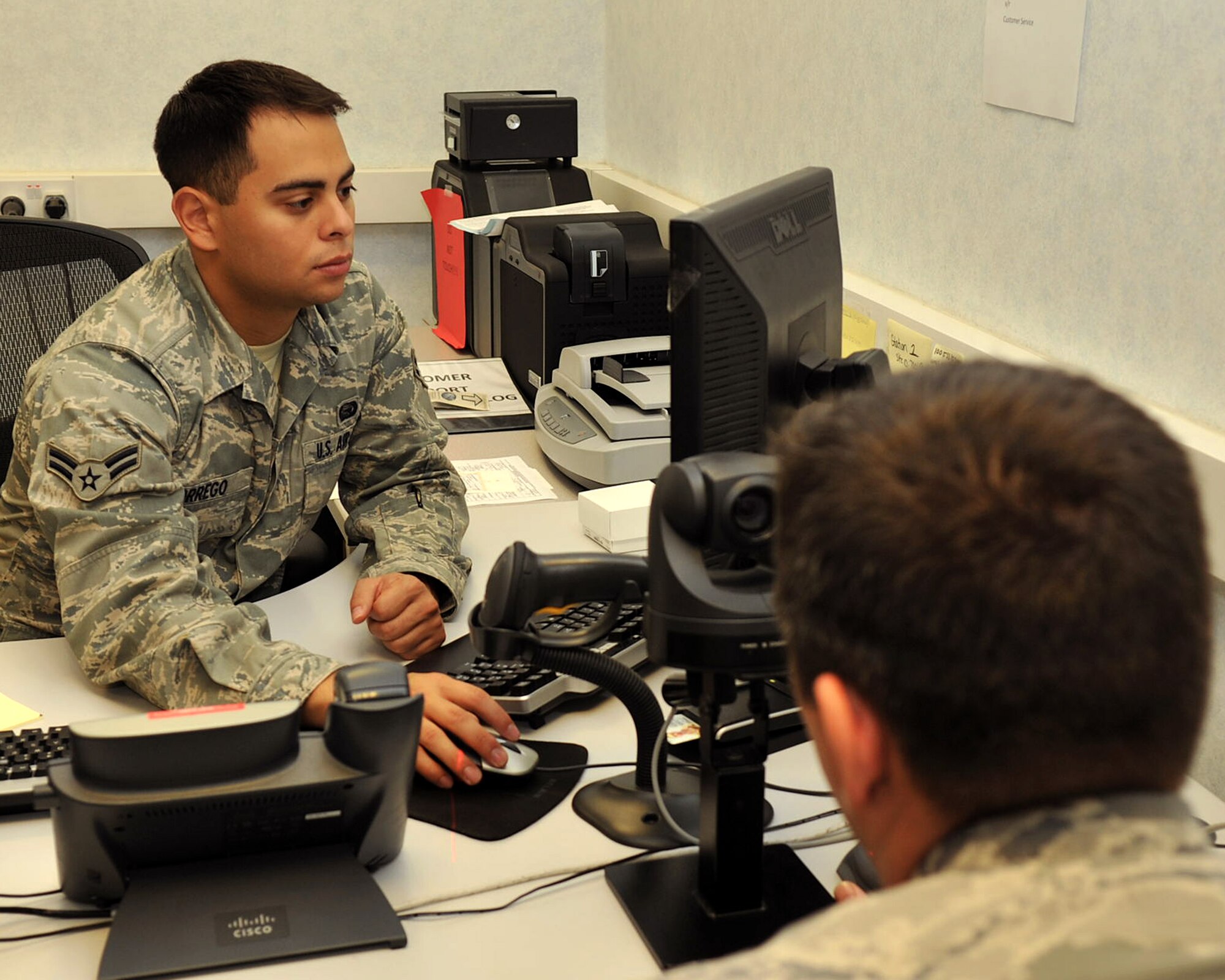 RAF MILDENHALL, England - Airman 1st Class Brian Orrego, 100th Force Support Squadron, assists an airman at the customer support desk of the military personnel section here Nov. 1, 2011. The section provides assistance including issuing and changing of common access cards and ration cards, issues with basic allowance for sustenance, and Defense Enrollment Eligibility Reporting System updates. (U.S. Air Force photo/Senior Airman Jerilyn Quintanilla)  