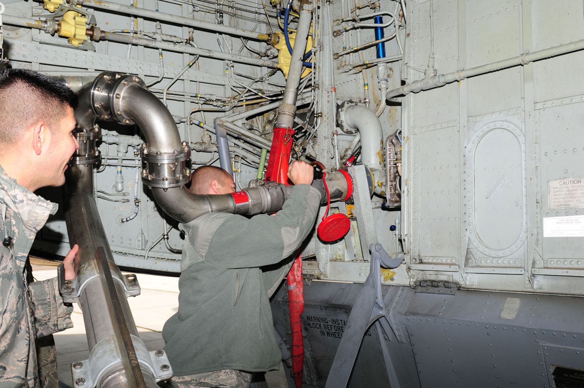 RAF MILDENHALL, England -- Staff Sgt. Joshua Pagel, right, 92nd Aircraft Maintenance Squadron crew chief, hooks up a fuel nozzle to the receptacle on a KC-135 Stratotanker from the 92nd Air Refueling Wing, Fairchild Air Force Base, Wash., as fellow 92nd AMXS crew chief, Staff Sgt. Robert Valdez, assists. Although fuels personnel from RAF Mildenhall connect the pantograph to the supply, they are not allowed to touch the connection that physically fits onto any transient aircraft. The aircraft belongs to another base, so the crew chiefs of the transient aircraft must do the final stages of connection before 100th LRS fuels Airmen complete the refueling. (U.S. Air Force photo/Karen Abeyasekere)