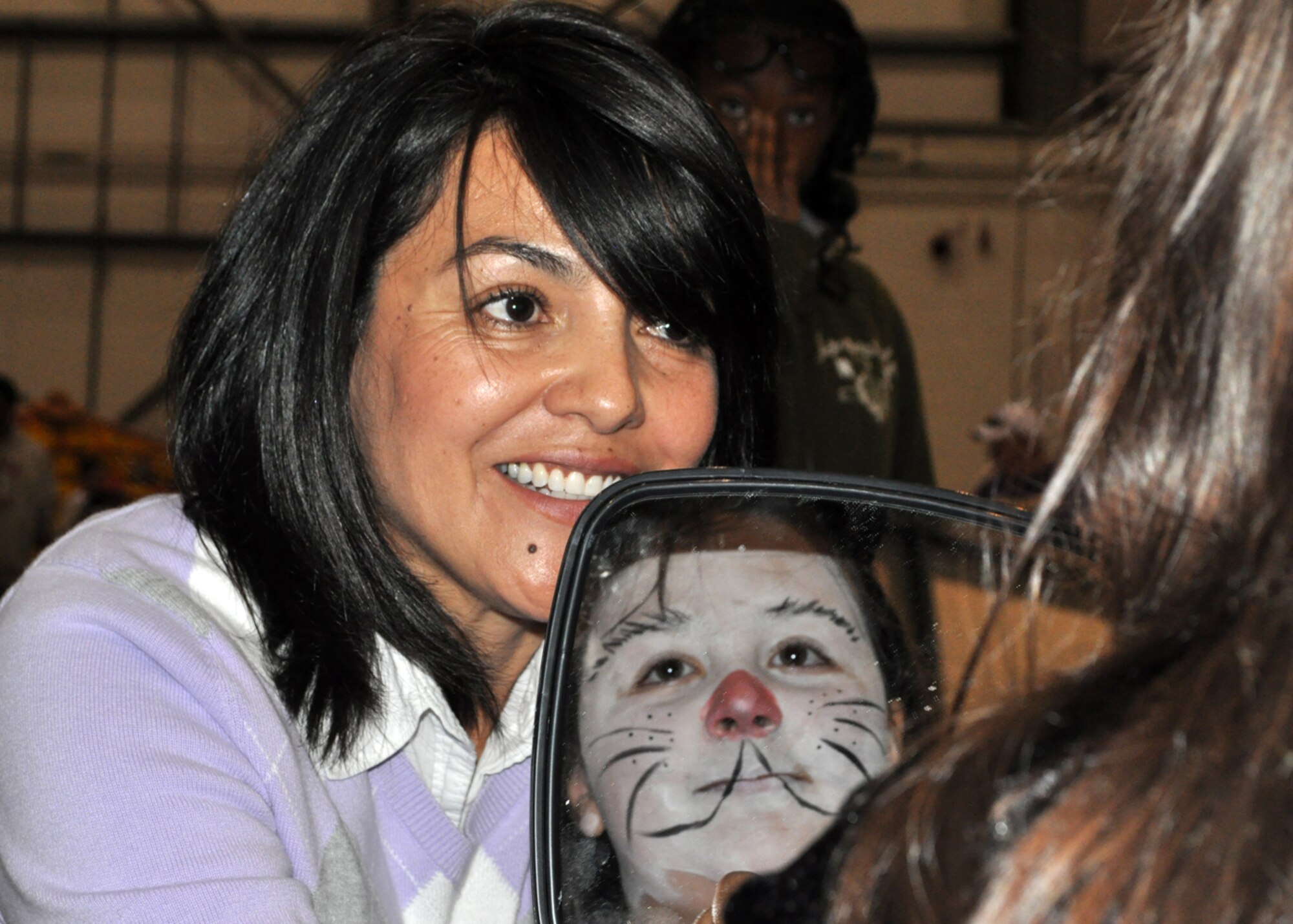 RAF MILDENHALL, England -- Sandra Gill, wife of Capt. Grant Gill, 352nd Special Operations Maintenance Squadron, gives 9-year-old Alice Hassan a chance to view her face-painting handiwork at the annual 352nd Special Operations Group Fall Fest here, Oct. 29, 2011.  Each year the 352nd SOG Spouses' Group hosts the event to promote camaraderie within the unit.  (U.S. Air Force photo/Tech. Sgt. Marelise Wood)  