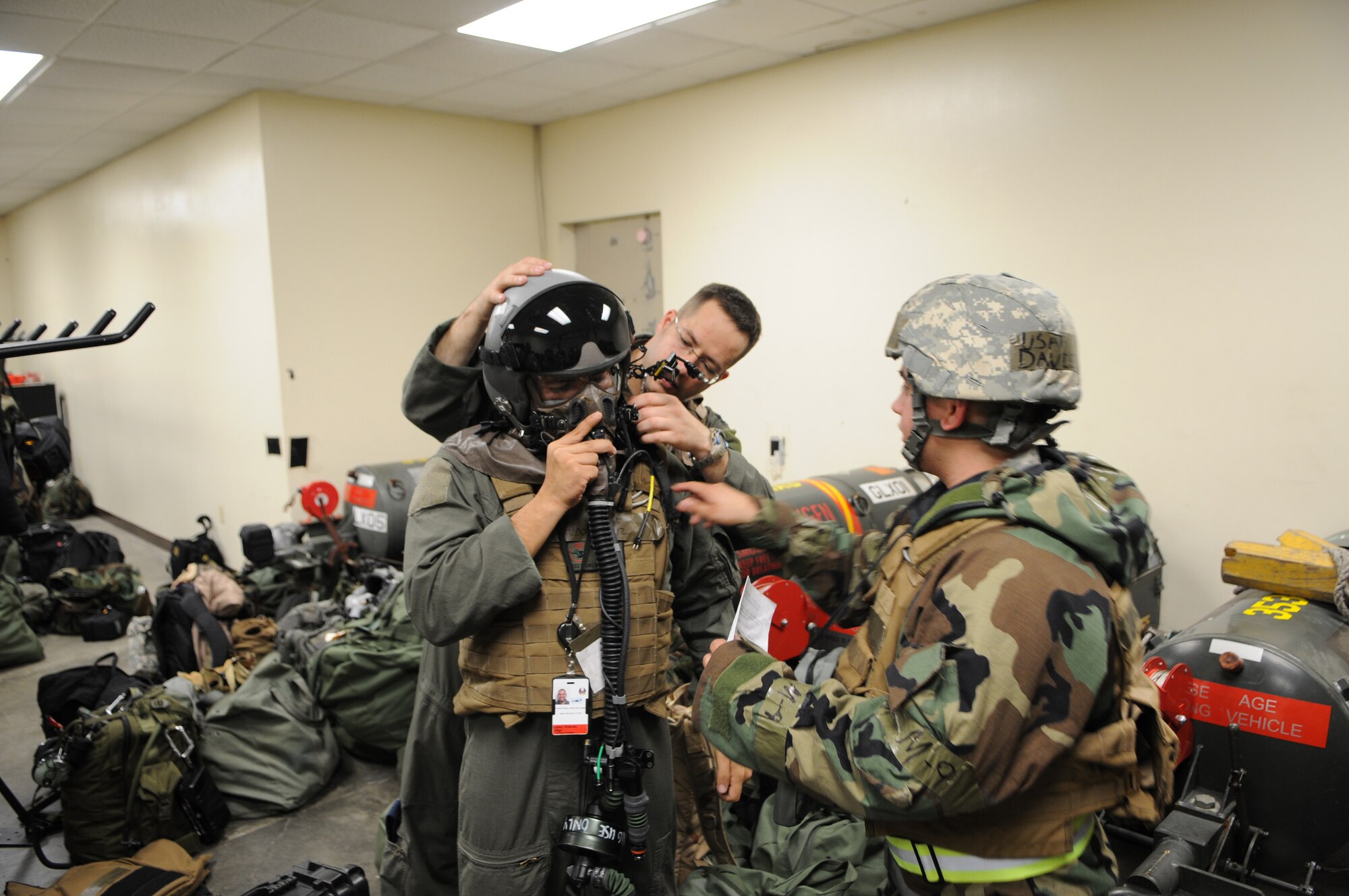 KADENA AIR BASE, Japan -- Capt.  Jason Gossett (back) and Airman 1st Class David Rodriguez (right) assist Staff Sgt. Orlando Lopez with donning his Aircrew Eye and Respiratory Protection System, or AERPS, during a local operational readiness exercise here Oct 26. The AERPS is an aircraft-integrated, self-contained oxygen and filtration system with aircraft-integrated electronics, communications and oxygen capabilities which allows the crews to continue their mission in a chemical warfare environment. (U.S. Air Force photo by Tech. Sgt. Aaron Cram)