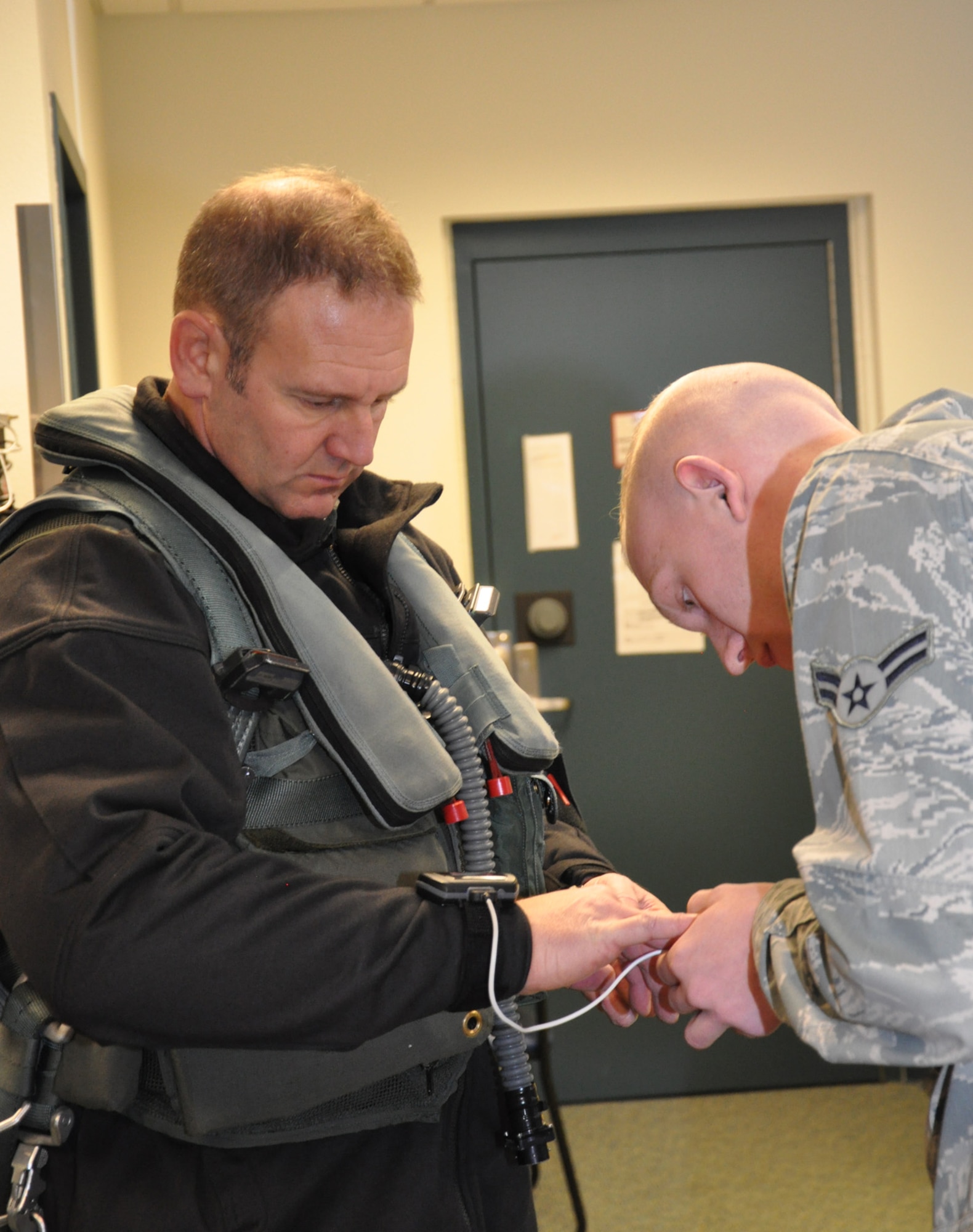 Col. Dirk Smith, 3rd Wing commander, dons a pulse oximeter on his right middle finger prior to flying a sortie with Lt. Col. David Piffarerio, 302nd Fighter Squadron commander. Piffarerio is the first Air Force pilot to reach 1,000 hours in the F-22.  (US Air Force photo/Capt. Ashley Conner)