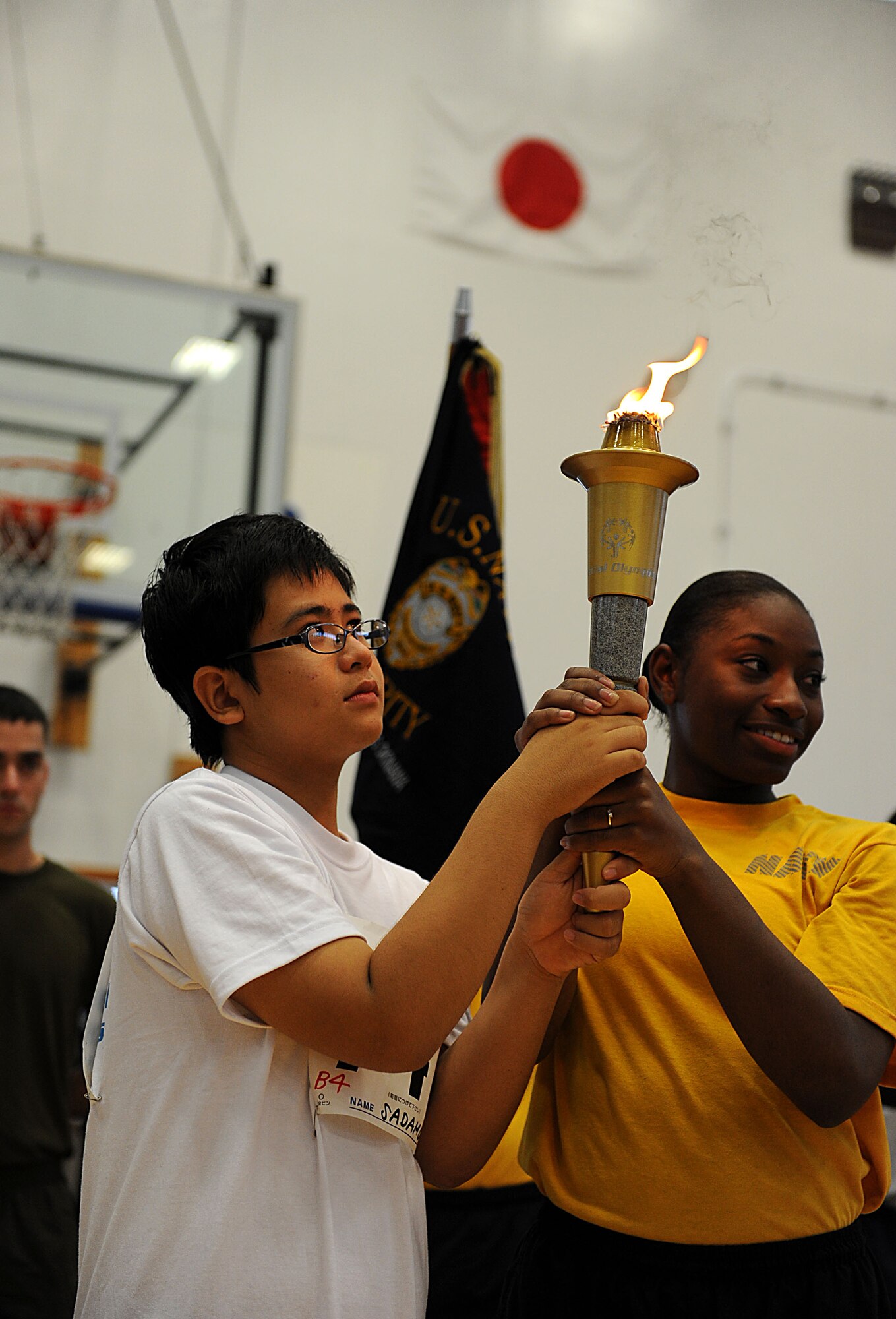Sadamun Malamute, a Kadena Special Olympics athlete, and U.S. Navy Master at arms Seamen Mieschia Sledge, present the torch at the start of the Kadena Special Olympics on Kadena Air Base, Japan, Nov. 5, 2011. More than 870 athletes participated in a variety of events ranging from 200 and 300 meter races, tennis skills and floor hockey to soccer skills and ground golf during the 12th Annual KSO. (U.S. Air Force photo/Airman 1st Class Brooke P. Beers/released)