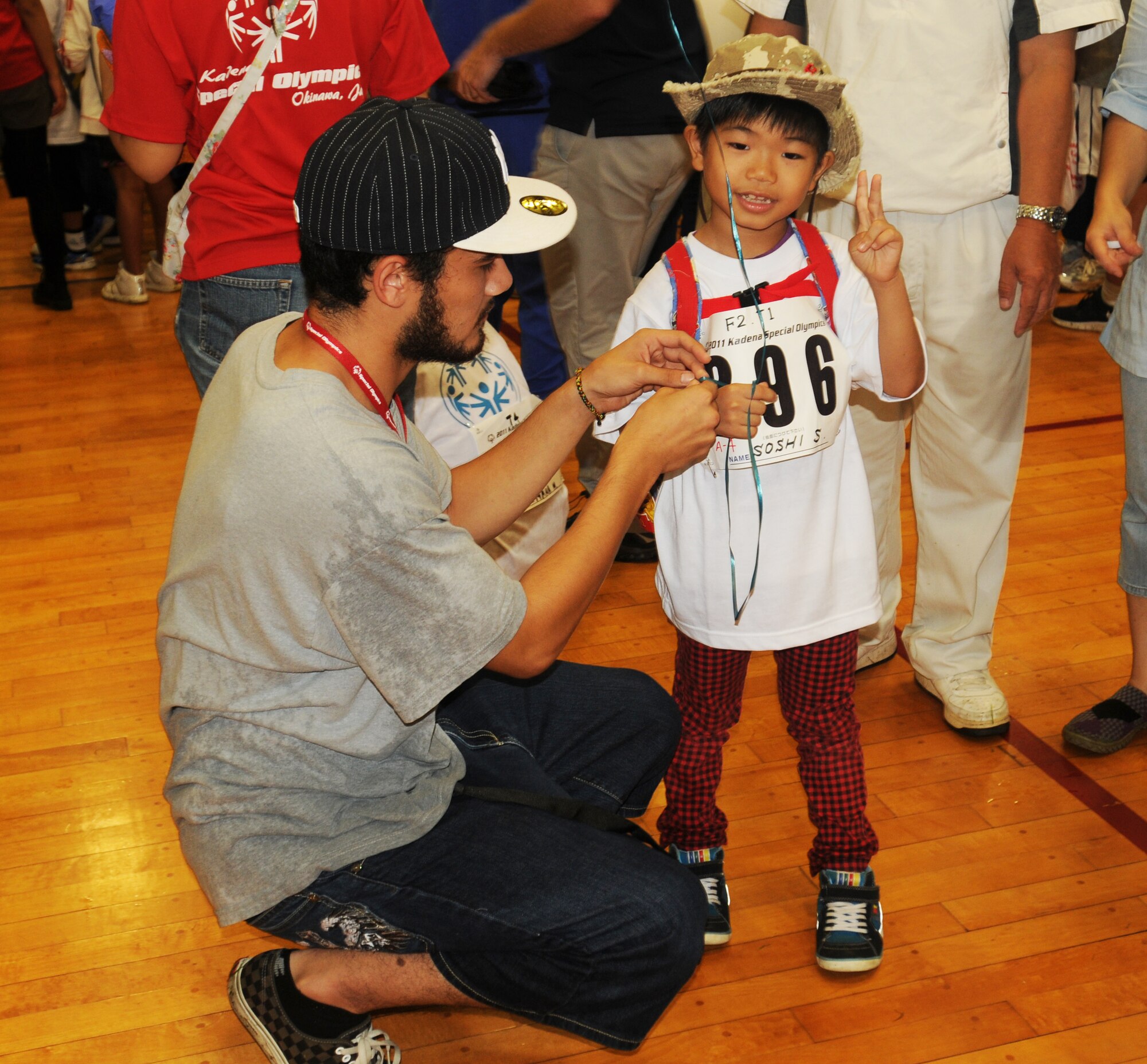 Cory Larkin, Kadena Special Olympics volunteer, helps 7-year-old Soshi, KSO athlete, tie a balloon on his wrist before the opening ceremony in the Risner Fitness Center on Kadena Air Base, Japan, Nov. 5, 2011. This year marks the 12th Annual KSO, a sporting event dedicated to enriching the lives of special-needs individuals while strengthening U.S. - Okinawa relationships. (U.S. Air Force photo/Tech. Sgt. Amanda Savannah/released)