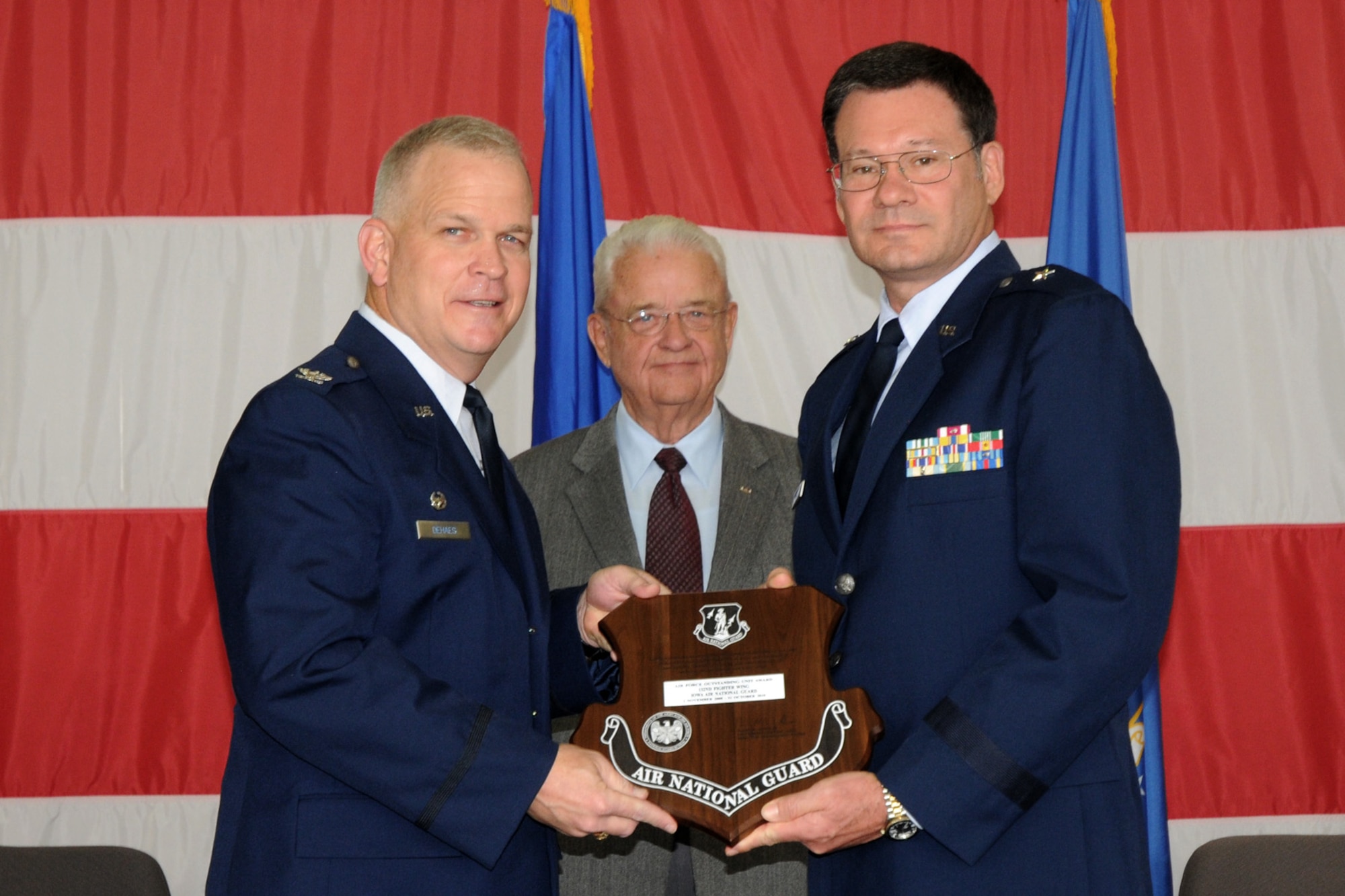 Brig. Gen. Derek Hill (right), Deputy Adjutant General of the IA Air National Guard, presents Col. Drew DeHaes (left), Commander of the 132nd Fighter Wing (132FW), Des Moines, Iowa with the Air Force Outstanding Unit award during the 2011 Awards Ceremony held in the hangar of the 132FW on November 6, 2011.  The Honorable Leonard Boswell (middle), Representative from the State of Iowa, observes.  (US Air Force photo/Staff Sgt. Linda E. Kephart)(Released)