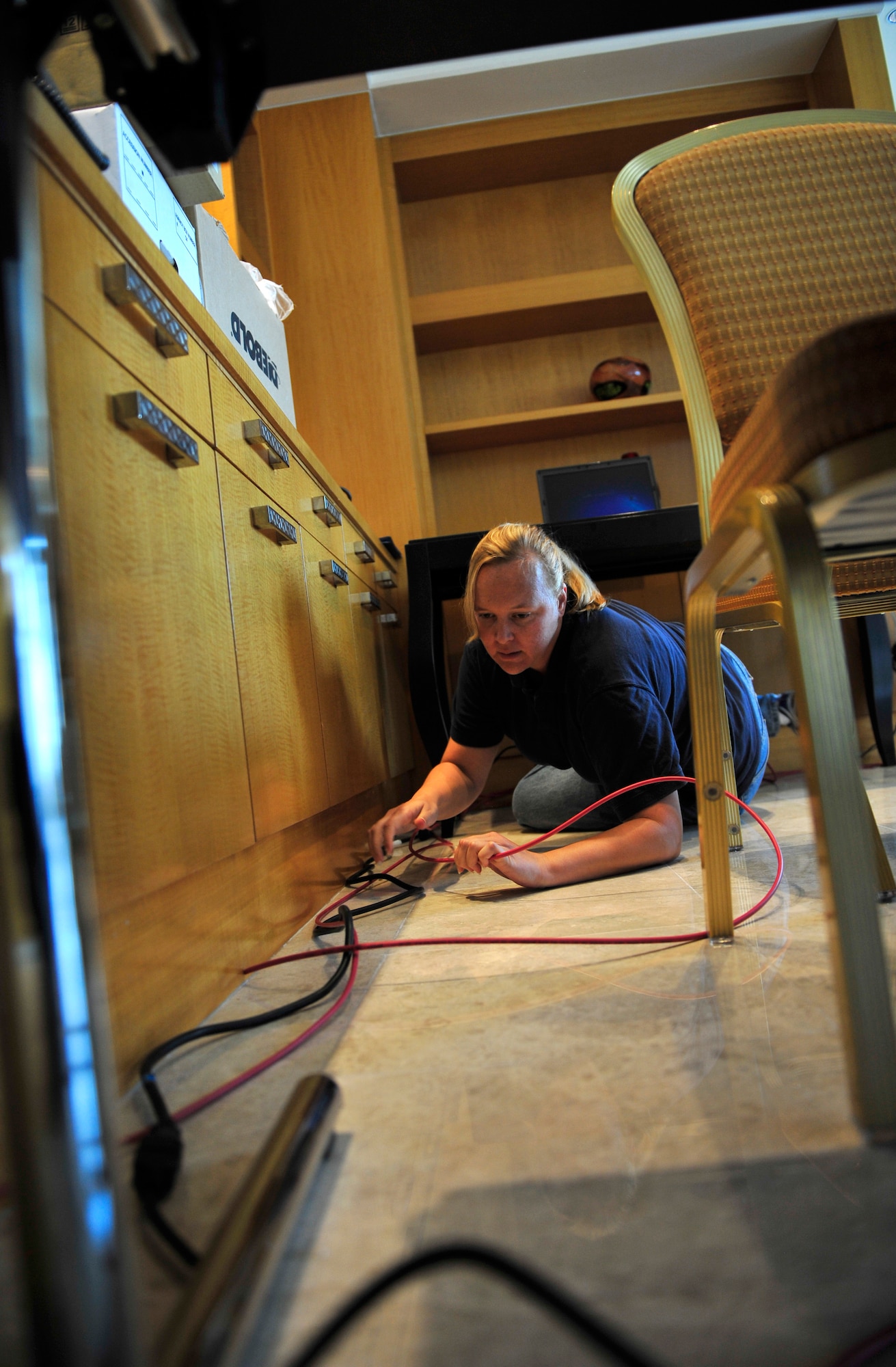 Amanda Campbell, a contractor with the 380th Expeditionary Communications Squadron, runs lines for a military communications network in one of the operations centers at the 2011 Dubai Airshow that will enable accountability of U.S. Air Force personnel at the event. Campbell is part of an 11-member communications team from U.S. Air Forces Central Command that was sent to Dubai to stand-up three operations centers for the 2011 Dubai Air Show. The operations centers will give U.S. military personnel access to military communications networks so they can check work email and reach back to their home units along with morale computers so they can stay in touch with friends and family members. Aircrew and support personnel from bases in the gulf region, Europe and the U.S. are participating in the Airshow, which is expected to draw more than 55,000 visitors. (U.S. Air Force Photo/Tech. Sgt. Patrick Mitchell)
