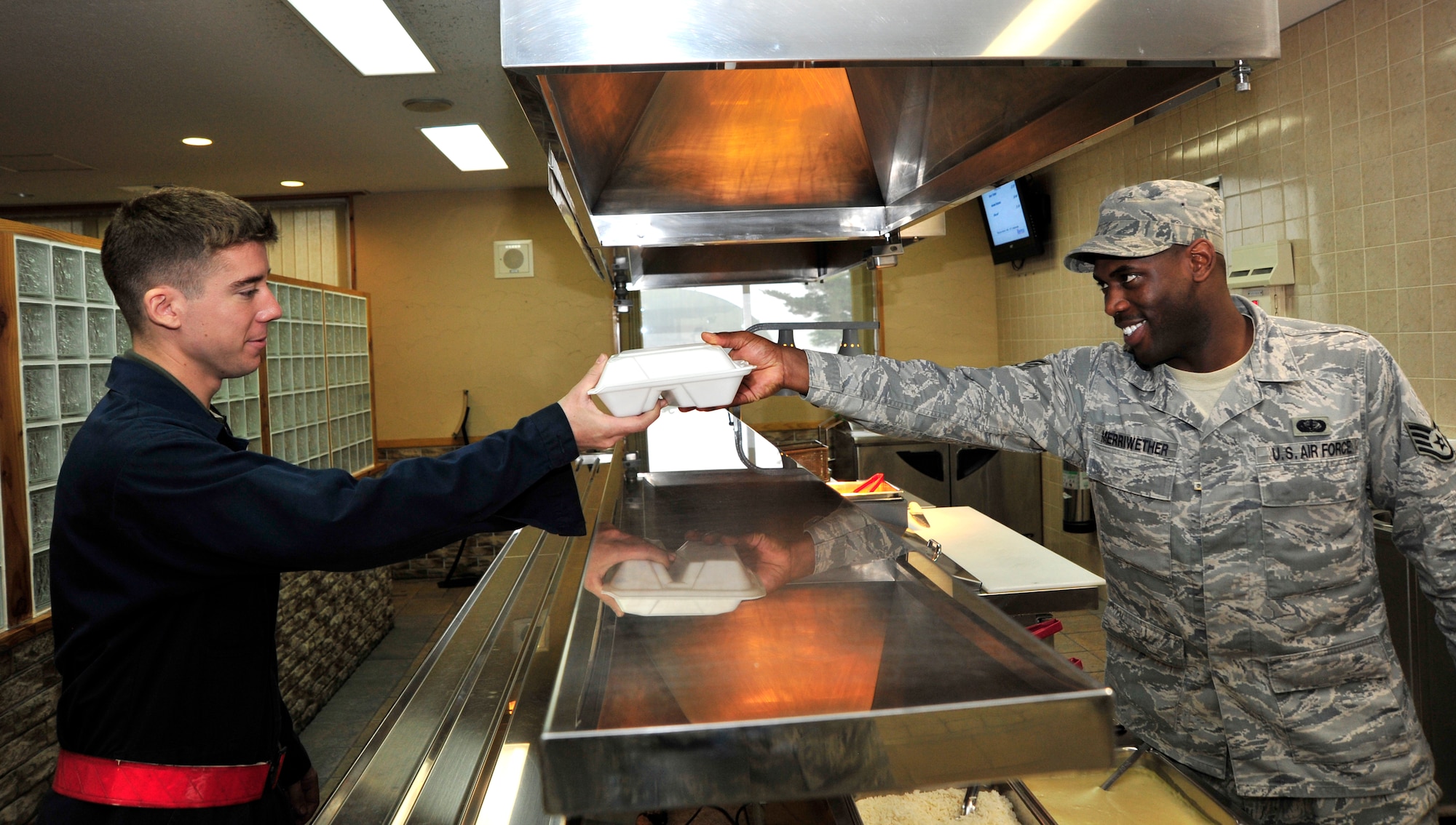 MISAWA AIR BASE, Japan – U.S. Air Force Senior Airman Skyler Rothganger, 14th Air Maintenance Unit, takes a quick break from fixing jets to grab a to go plate from Staff Sgt. Reid Merriwether, 35th Force Support Squadron Food Service Technician, at the Falcon Feeder dining facility during an operational readiness exercise here Nov. 6. The 35th Fighter Wing is currently going through an ORE in preparation for an operational readiness inspection in December. (U.S. Air Force photo/Staff Sgt. Nathan Lipscomb)