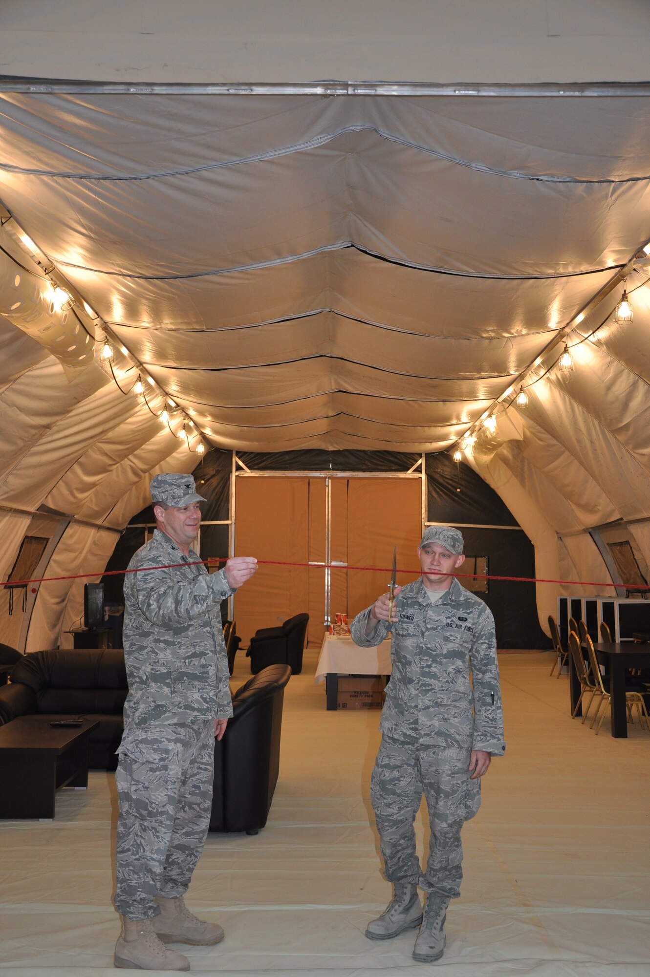 Col. William Summers, 386th Air Expeditionary Wing vice commander, and Airman 1st Class Dustin Turner, 386thExpeditionary Force Support Squadron lodging journeyman, celebrate the grand opening of an Morale, Welfare and Readiness tent Nov. 5 at an undisclosed location in Southwest Asia. (U.S. Air Force photo by Senior Airman Rachelle Elsea)