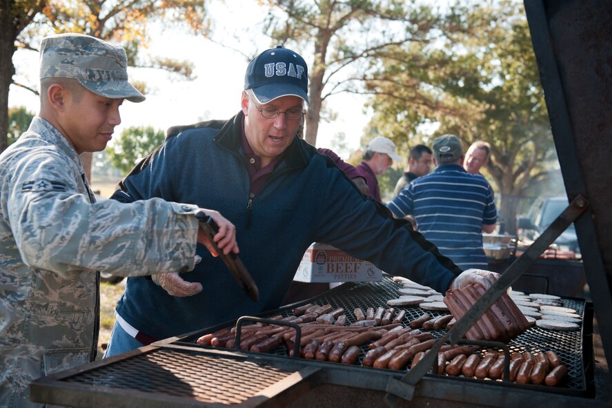 U.S. Air Force Airman 1st Class Ralf Koski, 23rd Security Forces Squadron member, left, and Chief Master Sgt. Dennis Lee, 23rd Civil Engineer Squadron superintendent, place and cook hotdogs on a grill during Retiree Appreciation Day at Moody Air Force Base, Ga., Nov. 5, 2011. To conclude Retiree Appreciation Week, Moody hosted several events which included an information fair, flu shots, static displays and a picnic. (U.S. Air Force photo by Staff Sgt. Jamal D. Sutter/Released)