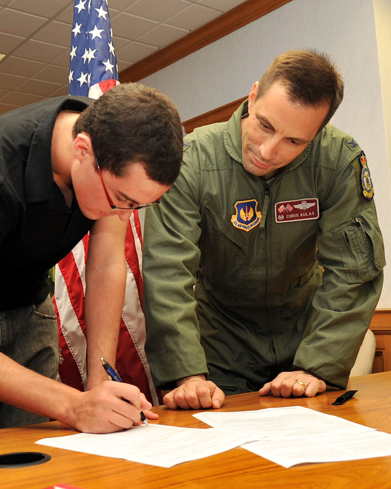 RAF MILDENHALL, England – Austin Powell, 18, signs his enlistment paperwork after taking his initial oath of enlistment into the U.S. Air Force here Nov. 3, 2011. Col. Christopher Kulas, 100th Air Refueling Wing commander, administered the oath. Powell is now in the delayed entry program waiting further testing for the Tactical Air Control Party program. (U.S. Air Force photo/Senior Airman Jerilyn Quintanilla)