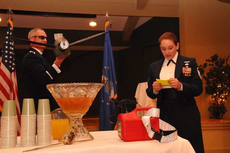 Master Sgt. Lori O'Connell prepares to 'fuel' the grog bowl as Lt. Col. Brian Davis holds the boom that will deliver the concoction to its bowl. The 916th Air Refueling Wing held its Dining Out and NCO Induction Ceremony on Nov. 5, 2011. (USAF photo by SrA Meredith A.H. Thomas, 916ARW/PA)