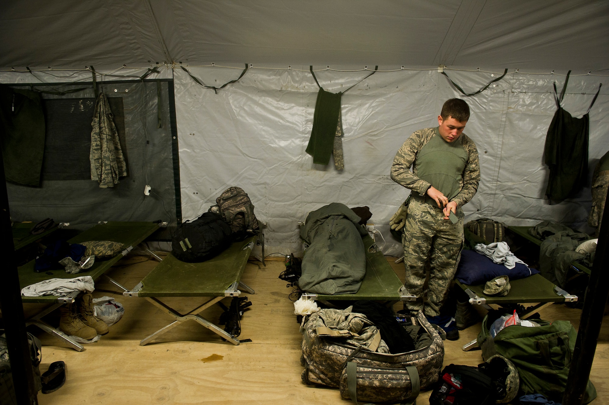 U.S. Air Force Airman 1st Class Tyler Bartlett, 70th medium truck detachment, gets dressed in a tent in Kalsu, Iraq after completing the second leg of a seven day convoy on Oct. 26, 2011.  As bases begin to shrink and personnel support services shut down, the sleeping accommodations for trucker crews become more limited. The team is taking 43 vehicles and 60 passengers more than 1,100 miles through Iraq to transport equipment and supplies out of the country in order to meet the military transition deadline. (U.S. Air Force Photo/Master Sgt. Jeffrey Allen)