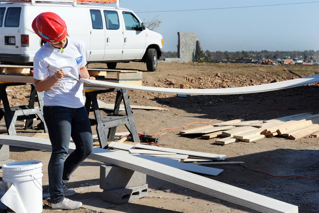 Air Force Airman 1st Class Nicole Magyari paints the end of a piece of siding as she and other airmen help Habitat for Humanity volunteers rebuild homes in Joplin, Mo., Nov. 1, 2011. Magyari is assigned to the 509th Civil Engineer Squadron at Whiteman Air Force Base, Mo.
