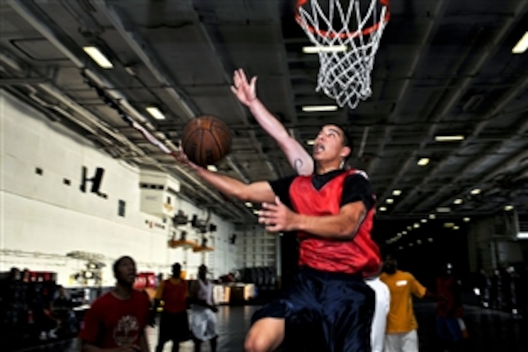 U.S. Navy Airman Apprentice Joe Morales attempts a lay up during a basketball tournament in the hangar bay of the aircraft carrier USS Ronald Reagan under way in the Pacific Ocean, Nov. 6, 2011. The Ronald Reagan is conducting operations at sea in support of Naval Air Training Command carrier qualifications.