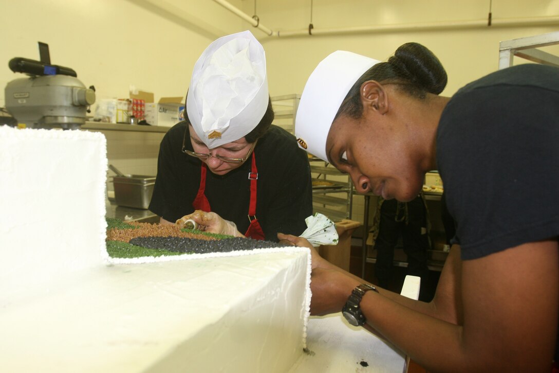 Staff Sgt. April L. Moss (right), from Columbus, Ohio, and Sgt. Amanda B. Auer (left), from Holyday, Fla., food service specialists with Combat Logistics Regiment 27, 2nd Marine Logistics Group, put the finishing touches on the cake for a Marine Corps’ birthday lunch celebration aboard Camp Lejeune, N.C., Nov. 8, 2011.   During the event food service Marines prepared steak and lobster, as well as a cake for everyone attending the lunch. (Photo by Cpl. Bruno J. Bego)