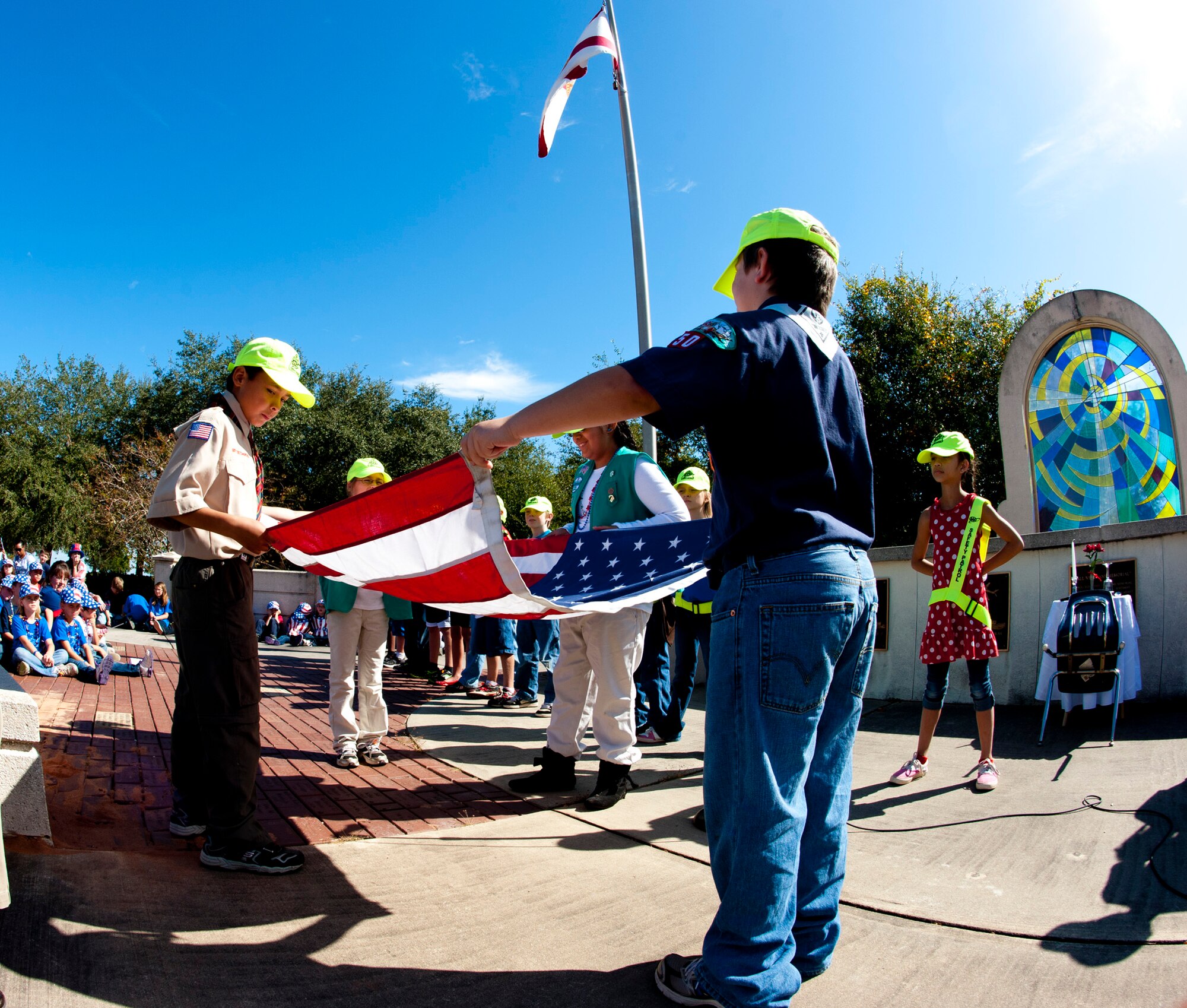 Girl and boy scouts fold the American flag during the annual Veteran's Day ceremony at the All Wars Memorial Nov. 8 at Eglin Air Force Base, Fla. More than 400 students attended the ceremony. (U.S. Air Force photo/Sachel Seabrook) 