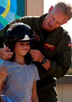 Cmdr. Scott Kartvedt, Strike Fighter Squadron 101, fits a new ‘pilot’ for her helmet during a Veterans Day ceremony at the All Wars Memorial at Eglin Air Force Base, Fla., Nov. 8. More than 400 students attended the ceremony.  (U.S. Air Force photo/Sachel Seabrook)