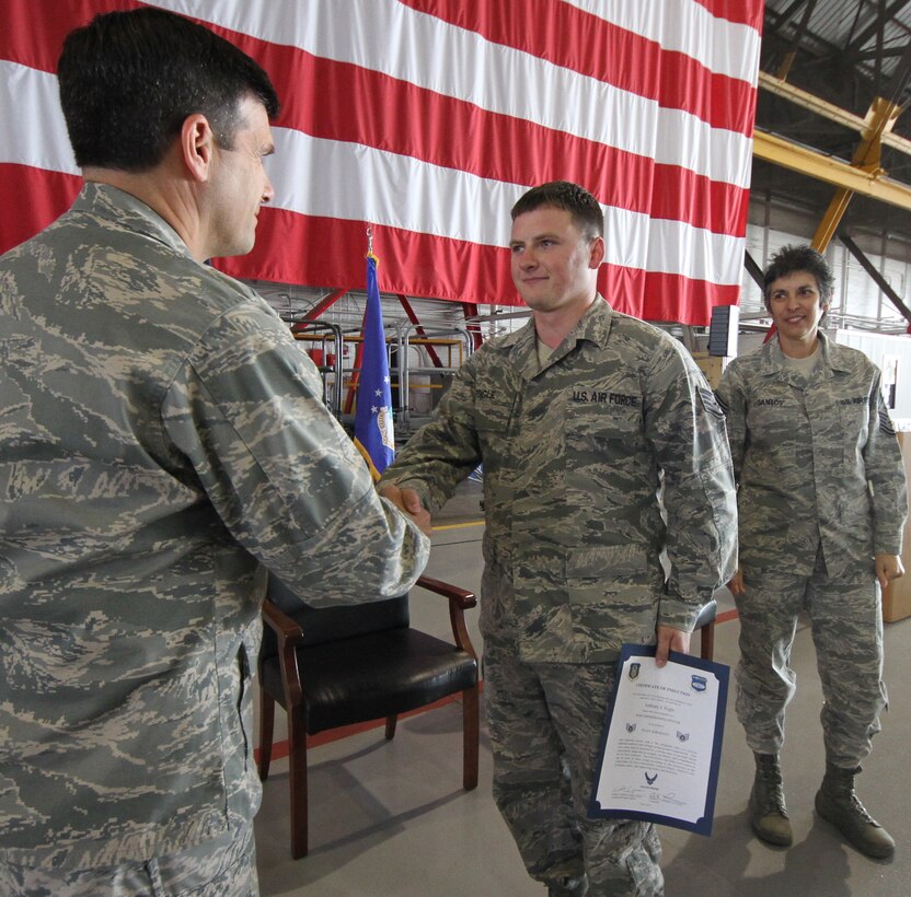 Col. Albert V. Lupenski, commander of the 932nd Airlift Wing, shakes hands with Staff Sgt. Anthony Fogle during the NCO induction ceremony.  At right, is Command Chief Master Sgt. Sandra Santos. Burrow and some 45 staff sergeants were newly inducted into the NCO ranks. Also, more than 35 master sergeants were inducted into the senior NCO ranks.  The program was held at the November monthly drill.      (U.S. Air Force photo/ Tech. Sgt. Christopher Parr)