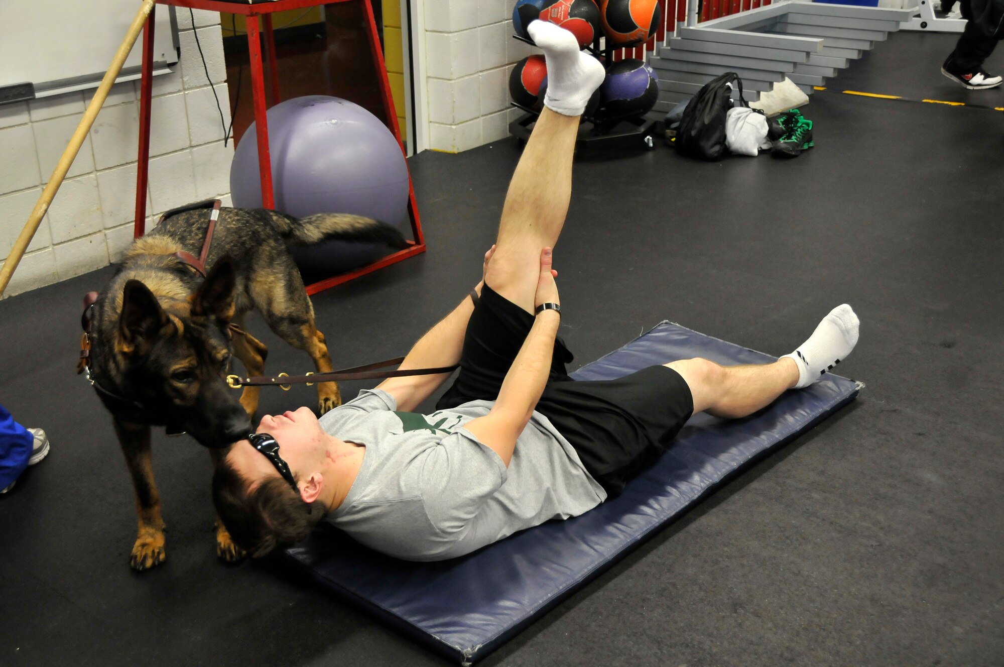 Senior Airman Michael Malarsie, 59th Patient Squadron, Lackland Air Force Base, Texas, stretches with his guide dog, Xxon, during an introduction to strength and conditioning training, part of an Adaptive Sports Wounded Warrior Mini Camp held by the Air Force at the Olympic Training Center and the U.S. Air Force Academy, Nov. 4. The camp ran from Nov. 3 to 6. (U.S. Air Force Photo/ Capt. George Tobias)