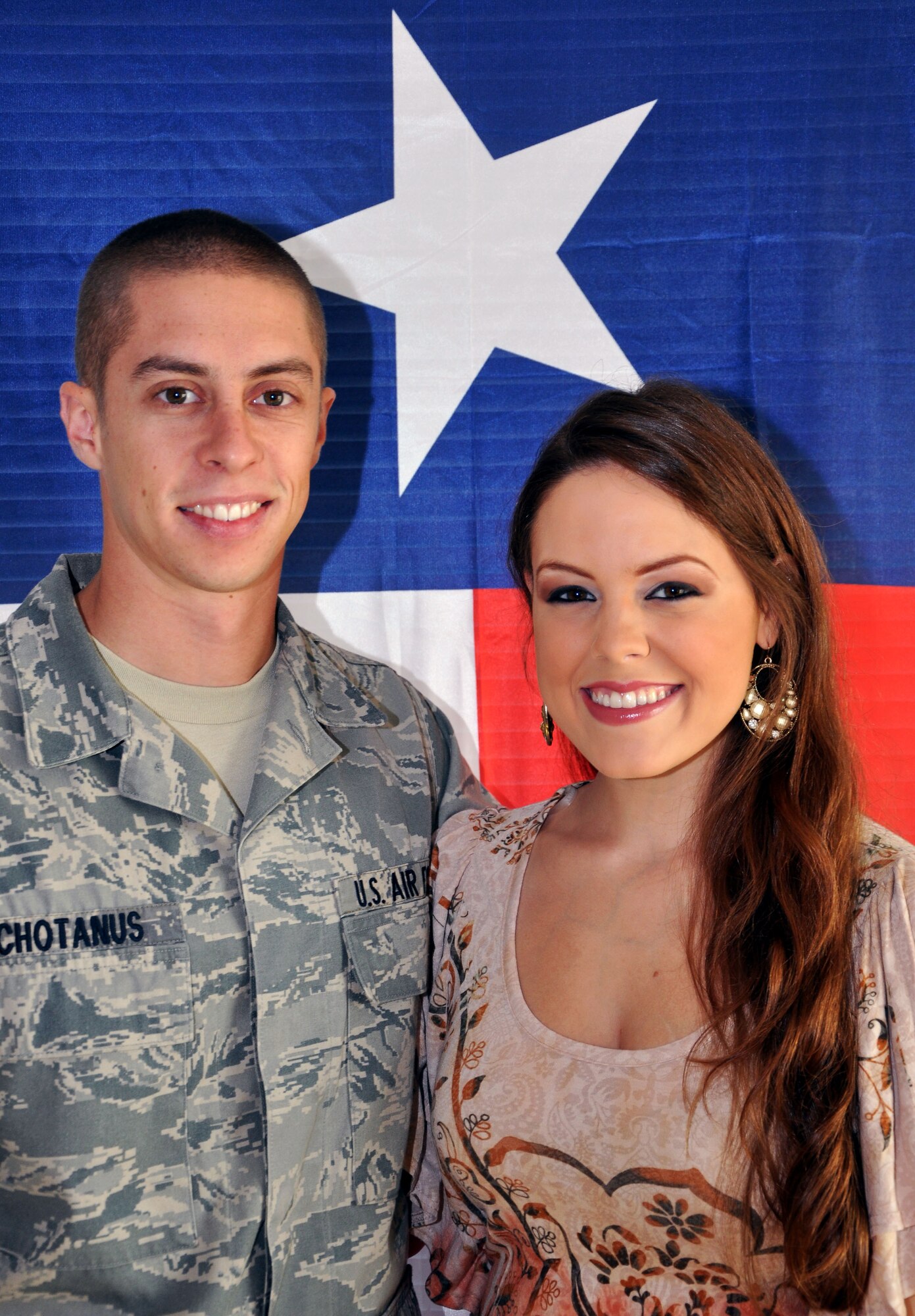 Airman 1st Class Alex Schotanus, 319th Comptroller Squadron finance technician, poses for a photo with wife, Cassie, in front of the Texas state flag at their home on Nov. 8 on Grand Forks Air Force Base, N.D. (U.S. Air Force photo/Airman 1st Class Derek VanHorn